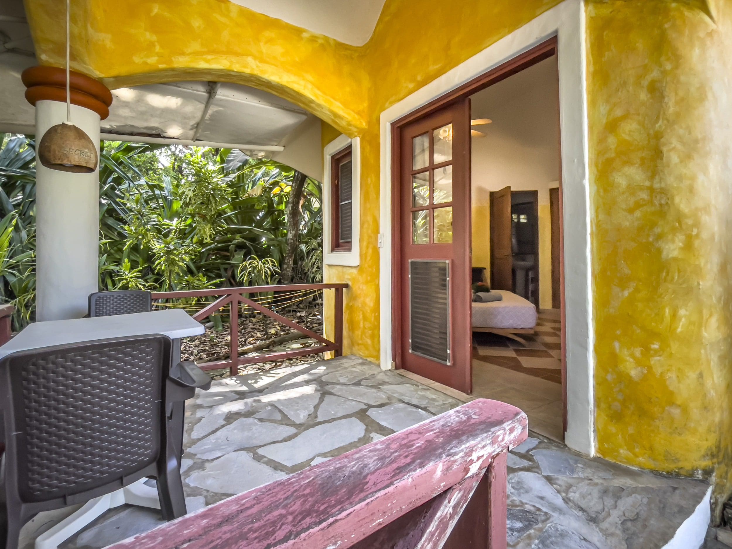 buyDRproperty Charming B&B porch with door open to bedroom, looking out to lush greenery. Sosua Real Estate