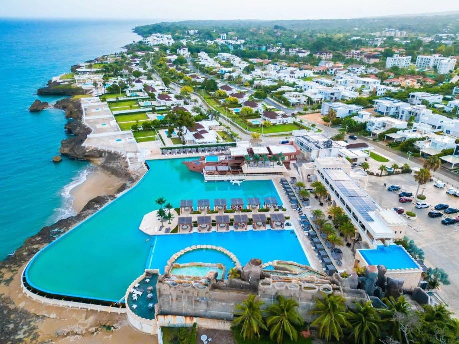 buyDRproperty Aerial view of a prime luxury resort with pools and cabanas near the ocean. Sosua Real Estate