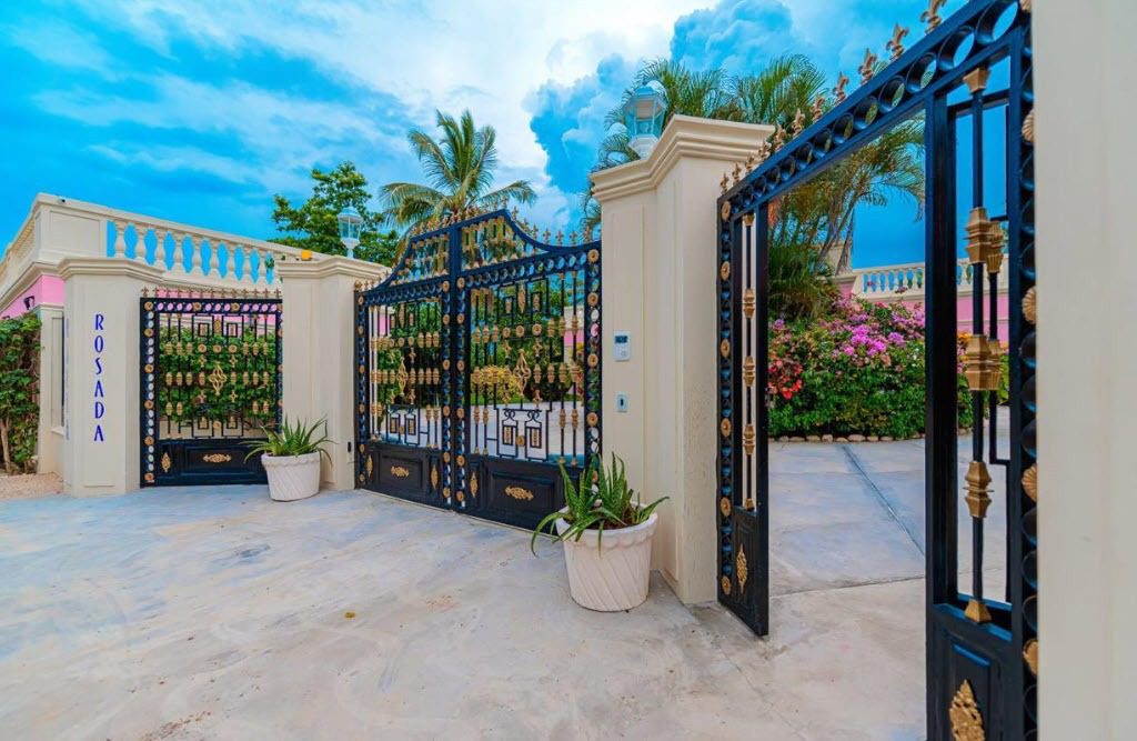 buyDRproperty Ornate black and gold gates lead to a prime villa entrance. "ROSADA" visible. Sosua Real Estate