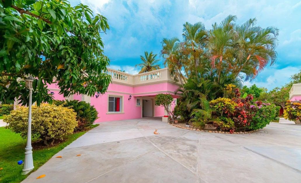 buyDRproperty Pink villa with lush landscaping, prime location near beach. Sosua Real Estate