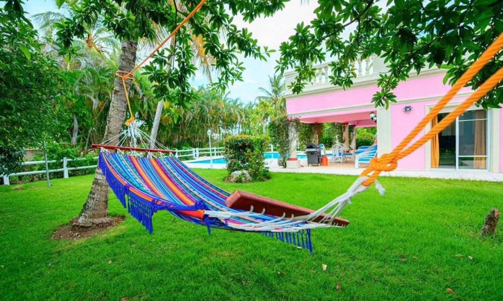buyDRproperty Hammock strung between trees in front of a pink villa near the beach, prime location. Sosua Real Estate