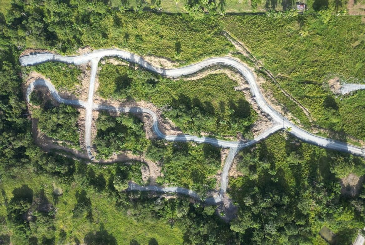 buyDRproperty Aerial view of winding roads through lush green landscape, potentially for a new housing development. Sosua Real Estate
