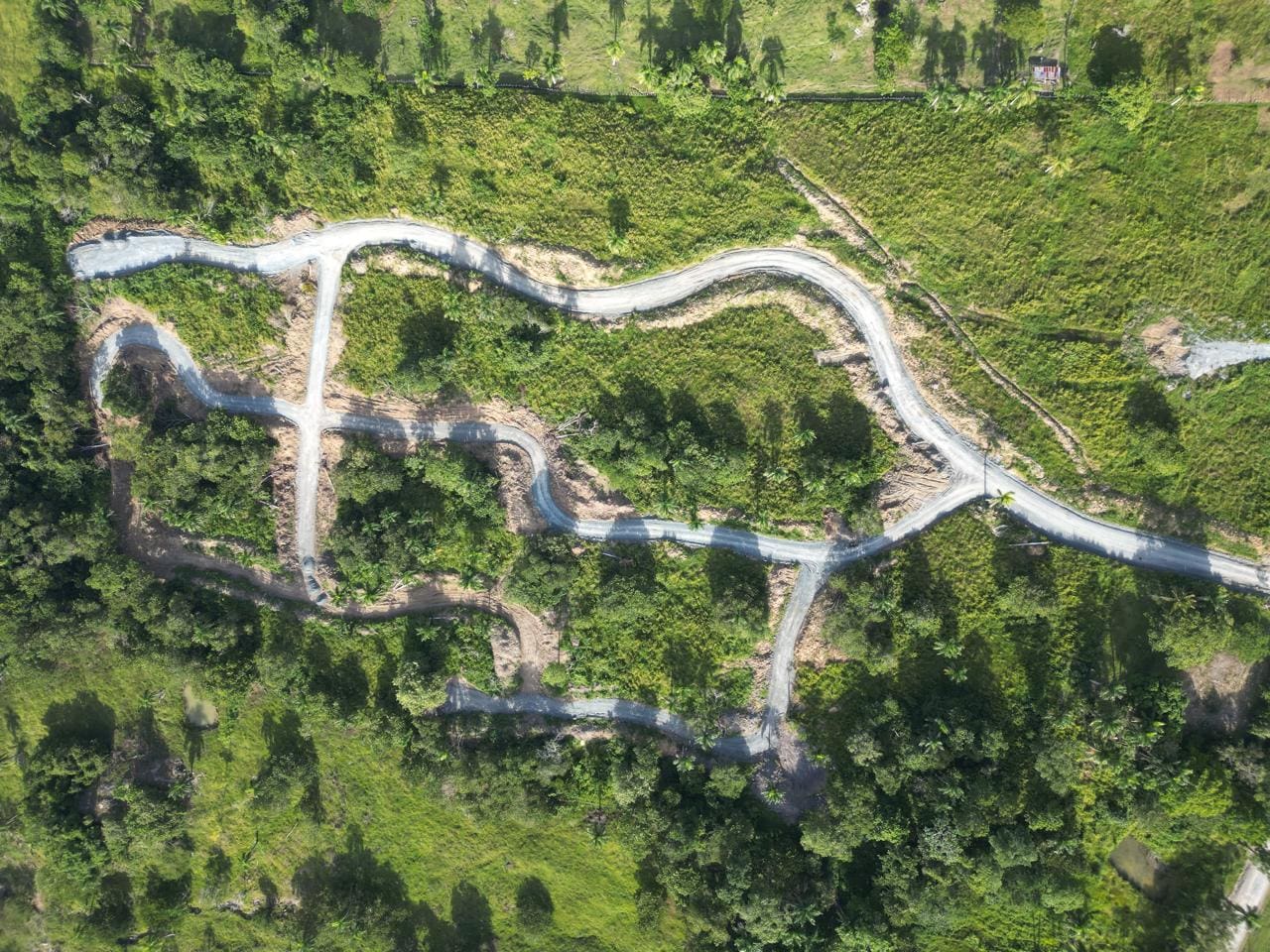 buyDRproperty Aerial view of winding roads through lush green landscape, potentially for a new housing development. Sosua Real Estate