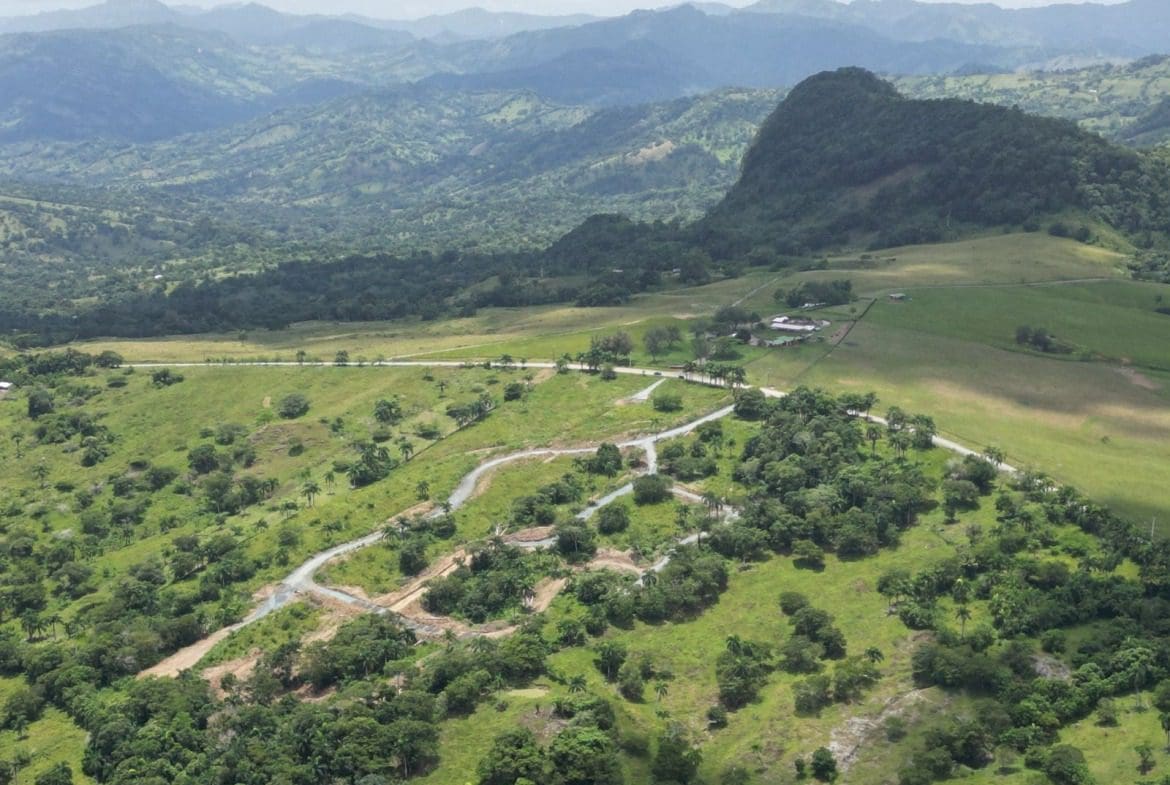 buyDRproperty Scenic view of green hills and mountains with a winding road and houses. Sosua Real Estate