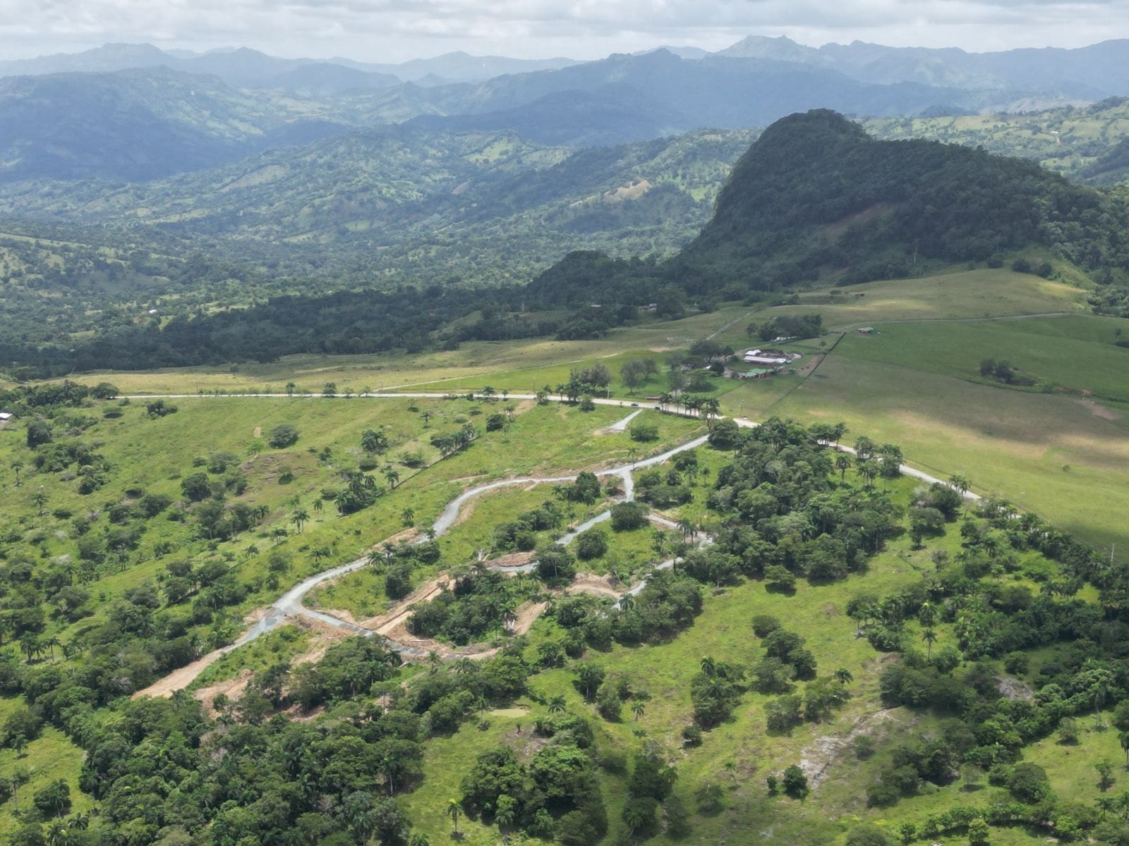 buyDRproperty Panoramic view of green hills and mountains with road winding through Sosua Real Estate