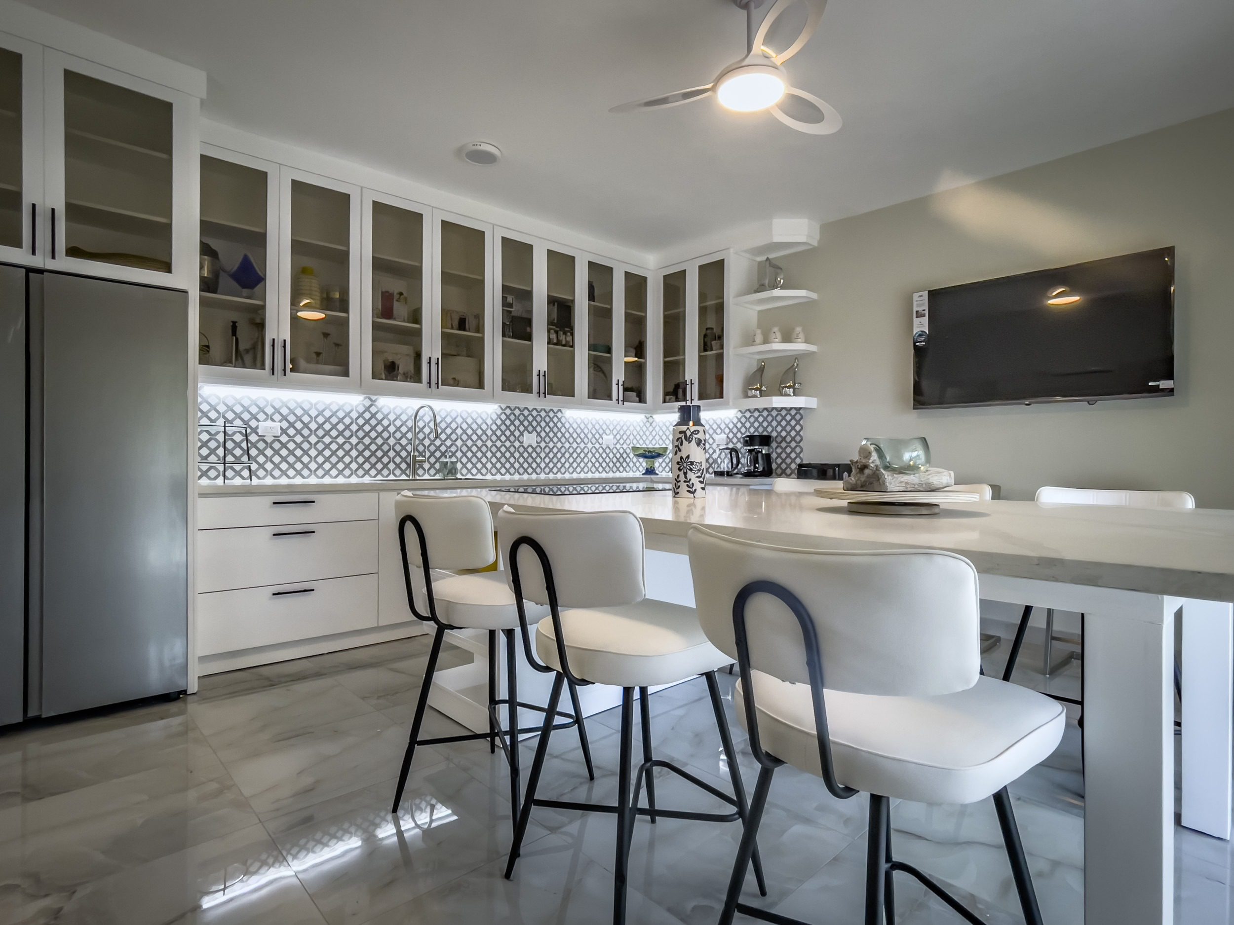 buyDRproperty Modern kitchen with white cabinets, bar stools, and a marble countertop. Offers modern comfort. Sosua Real Estate