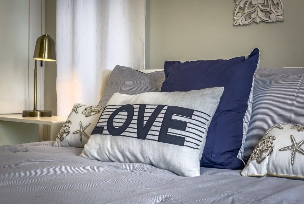 buyDRproperty Coastal bedroom with "LOVE" pillow, offering modern comfort. Sosua Real Estate