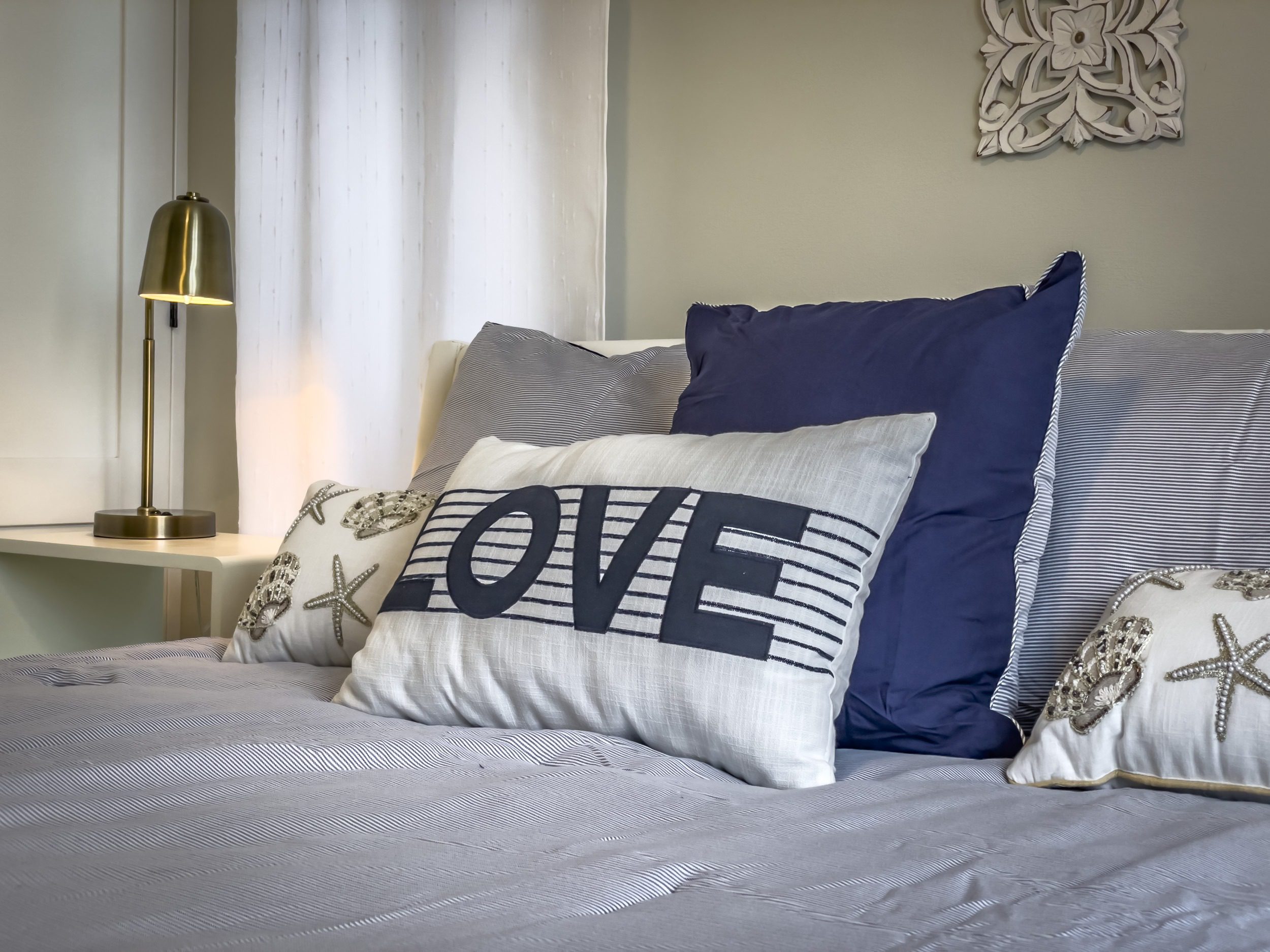buyDRproperty Coastal bedroom with "LOVE" pillow, offering modern comfort. Sosua Real Estate