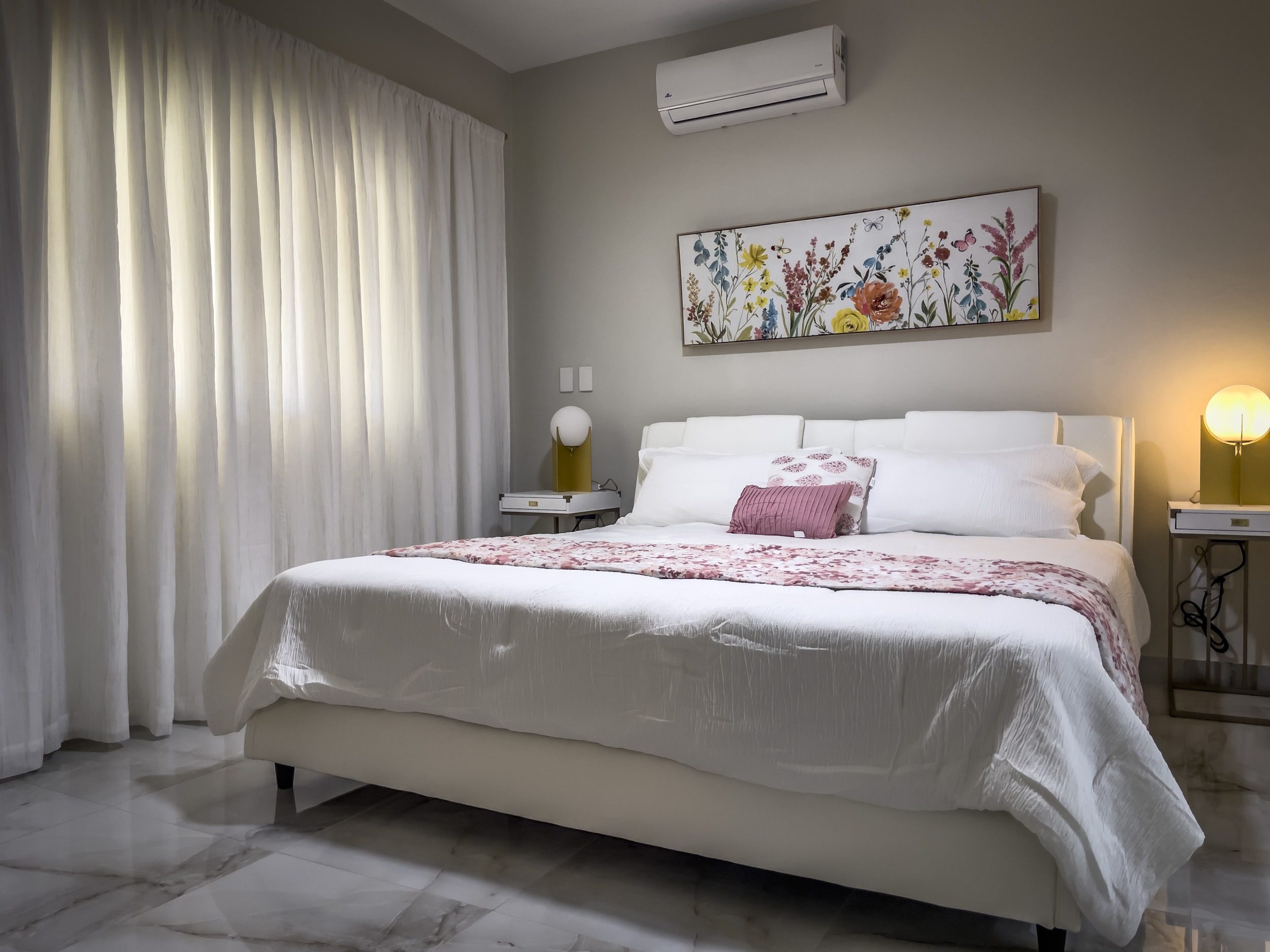 buyDRproperty Modern bedroom with a large bed, floral artwork, and soft lighting, offering modern comfort. Sosua Real Estate