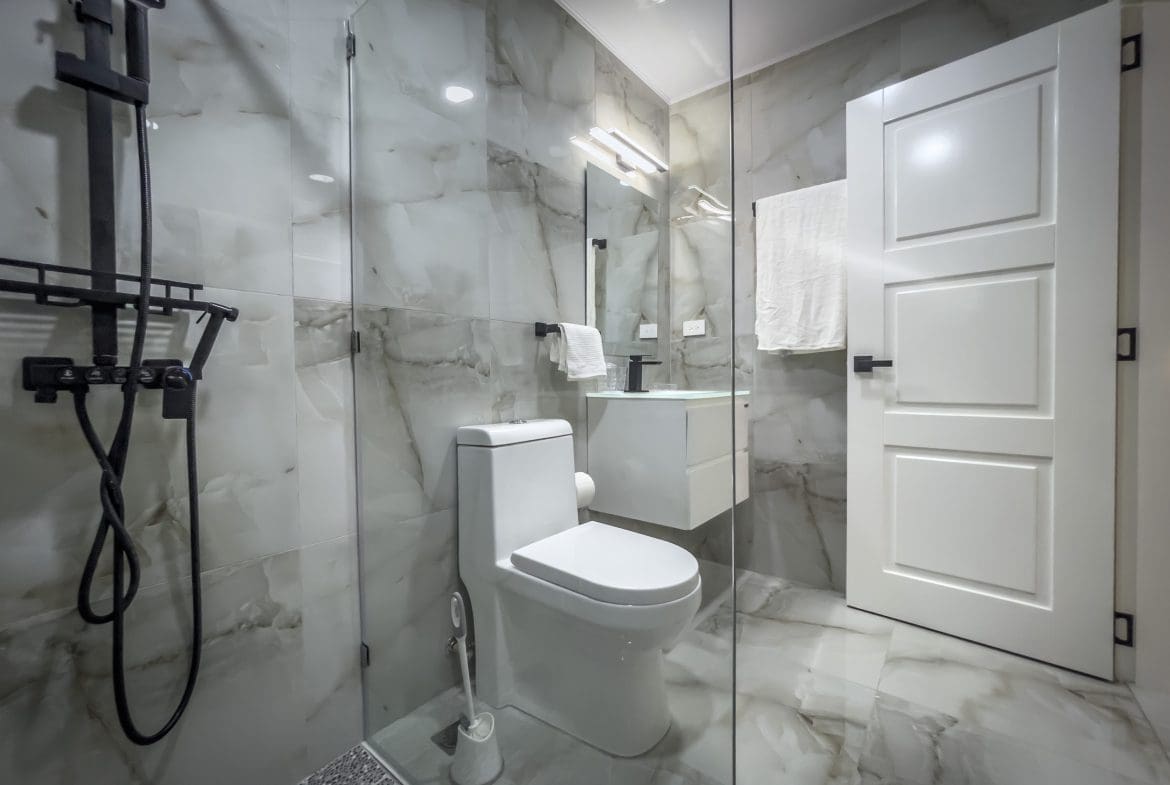 buyDRproperty Modern bathroom with marble tiles and black fixtures, offering modern comfort. Sosua Real Estate
