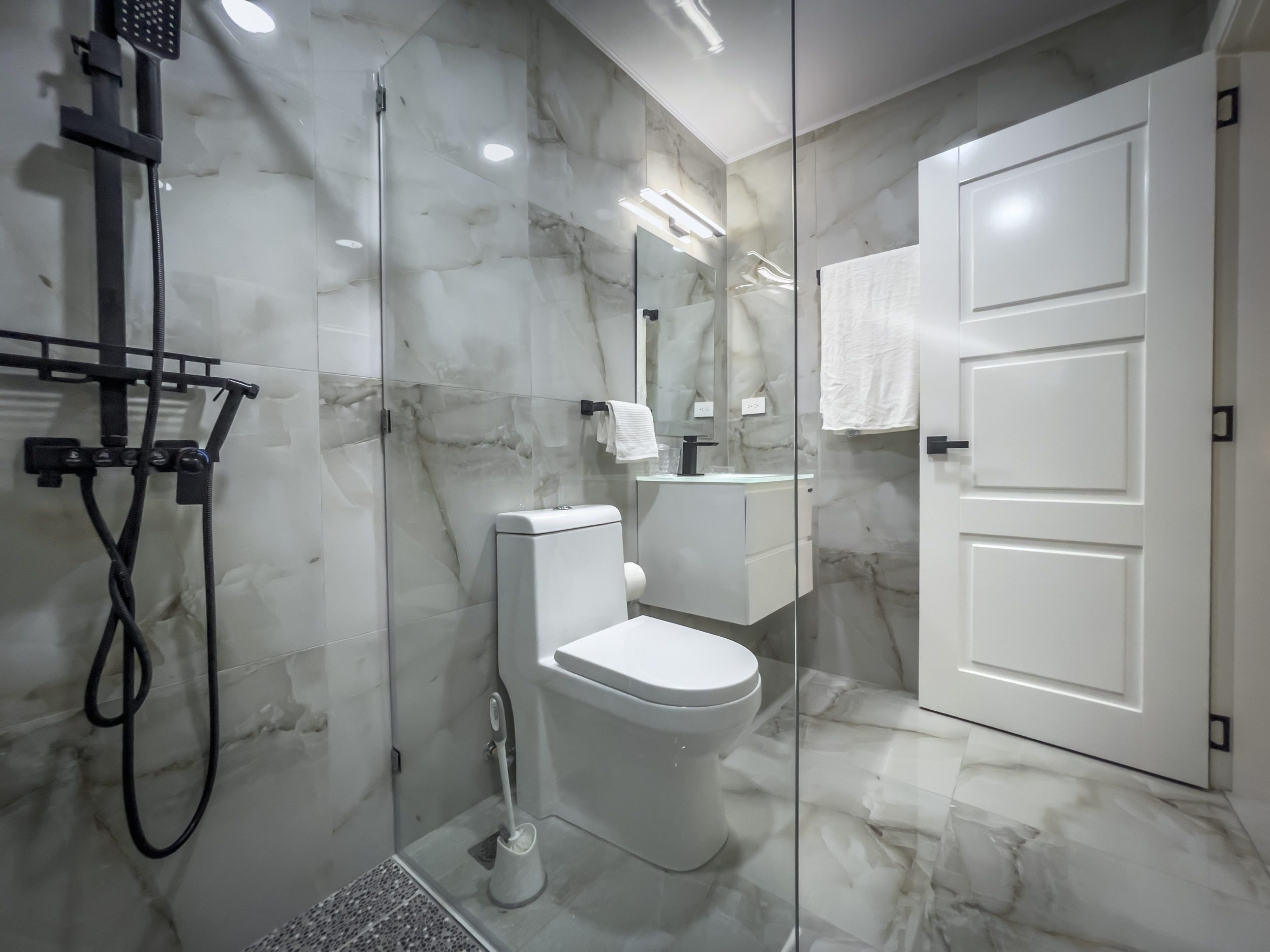 buyDRproperty Modern bathroom with marble tiles and black fixtures, offering modern comfort. Sosua Real Estate
