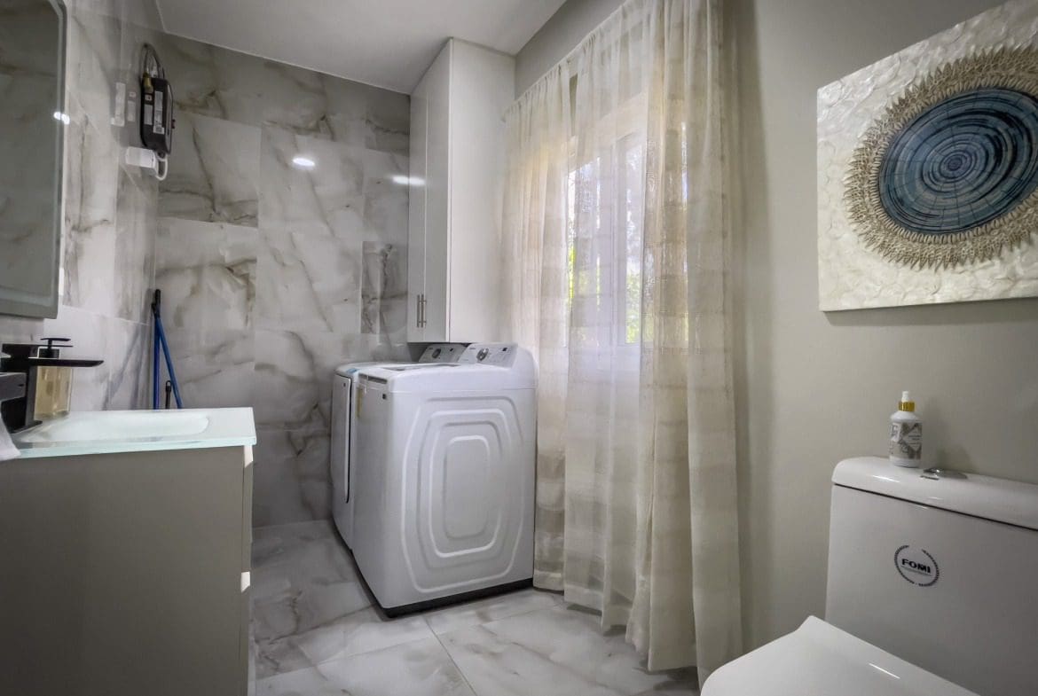 buyDRproperty Modern laundry room with white appliances and marble tile, offering modern comfort. Sosua Real Estate