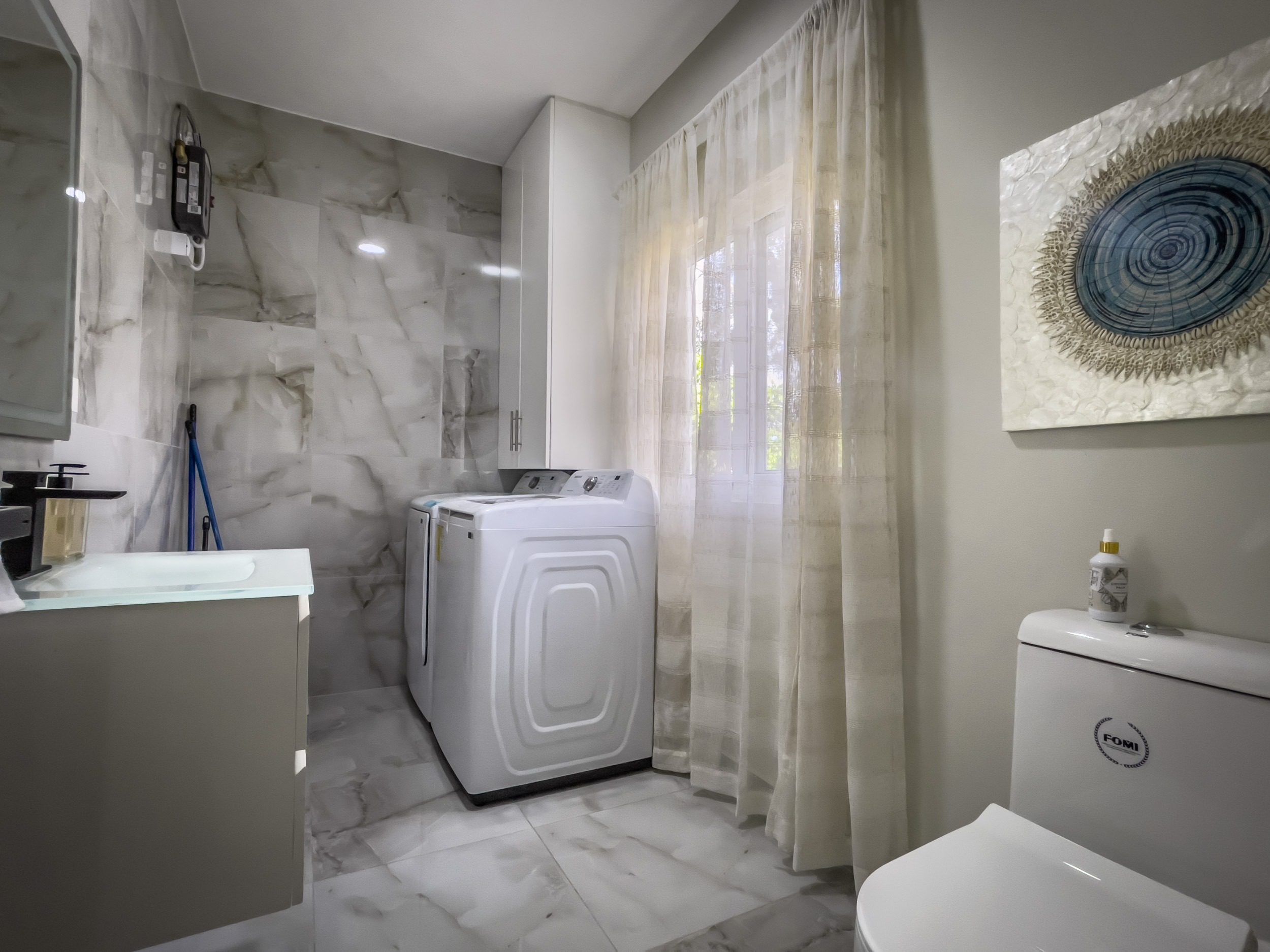 buyDRproperty Modern laundry room with white appliances and marble tile, offering modern comfort. Sosua Real Estate