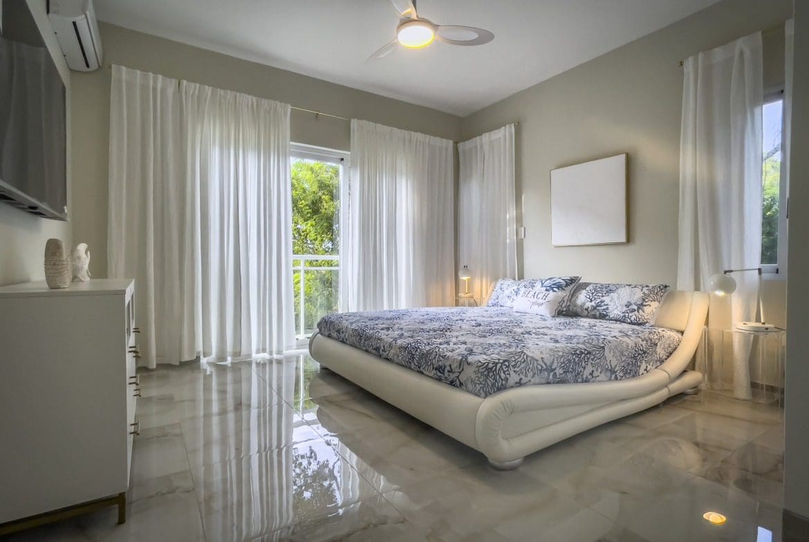 buyDRproperty Modern bedroom with a large bed, white curtains, and marble floor, offering modern comfort. Sosua Real Estate