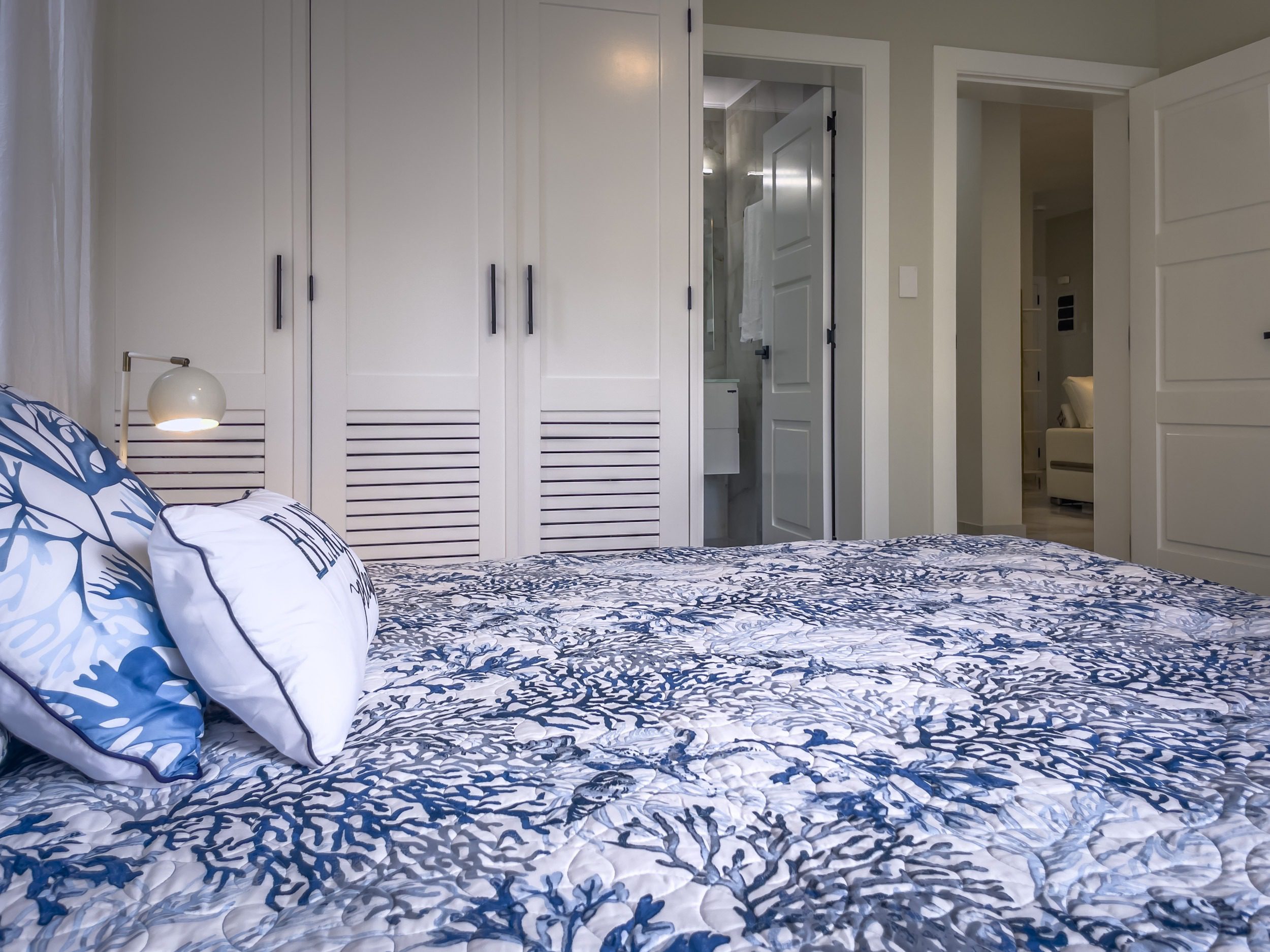 buyDRproperty Bedroom with blue coral quilt, white wardrobes, and modern comfort. Sosua Real Estate
