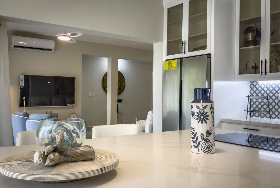 buyDRproperty Modern kitchen with white cabinets, a decorative vase, and a view into the living room. Sosua Real Estate