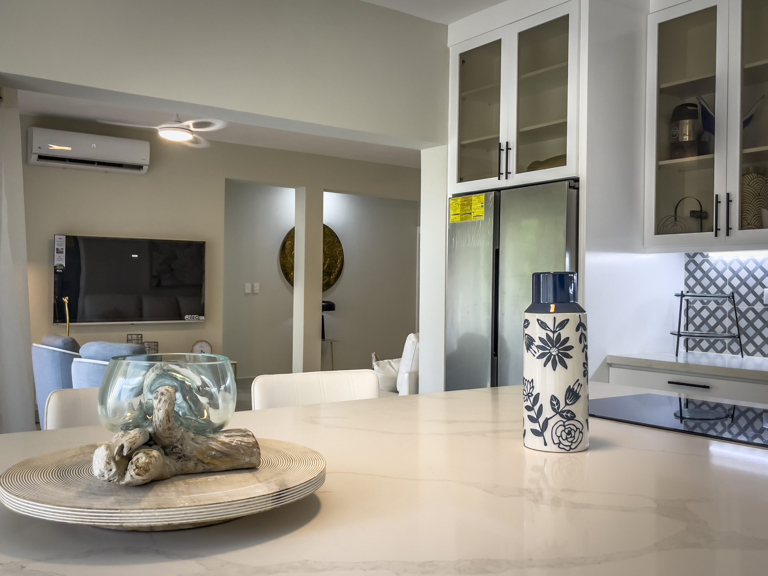 buyDRproperty Modern kitchen with white cabinets, a decorative vase, and a view into the living room. Sosua Real Estate