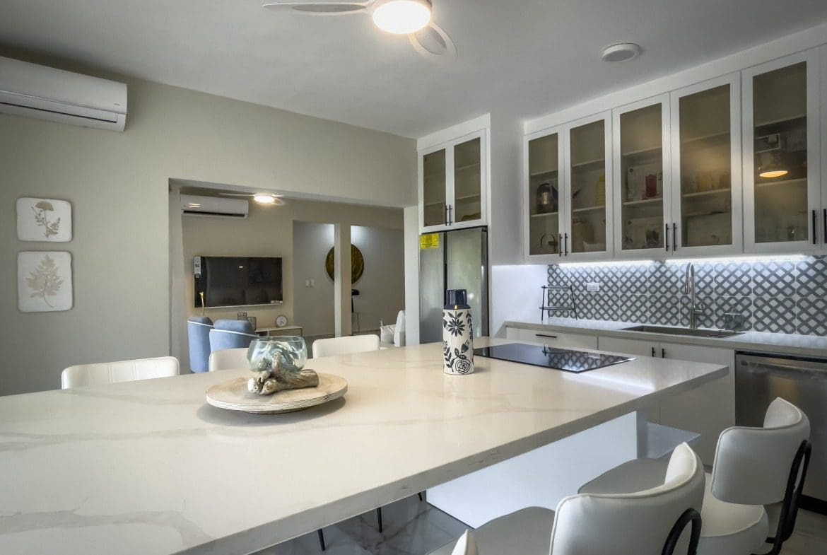 buyDRproperty Modern kitchen with white cabinets and a large island, offering modern comfort. Sosua Real Estate