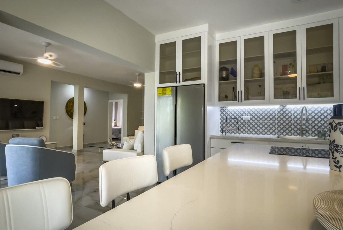 buyDRproperty Modern kitchen with white cabinets, stainless steel refrigerator, and white countertop, offering modern comfort. Sosua Real Estate