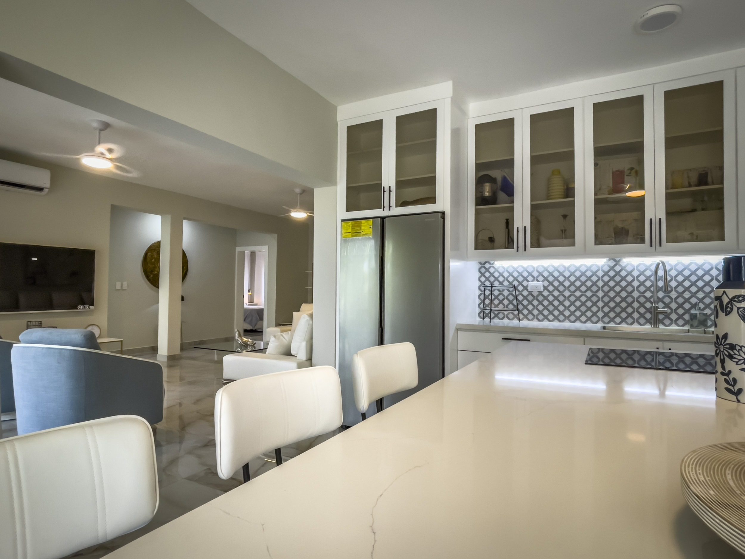 buyDRproperty Modern kitchen with white cabinets, stainless steel refrigerator, and white countertop, offering modern comfort. Sosua Real Estate