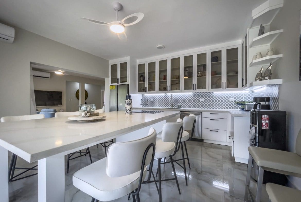 buyDRproperty Modern kitchen with white cabinets, island seating, and a ceiling fan. Sosua Real Estate