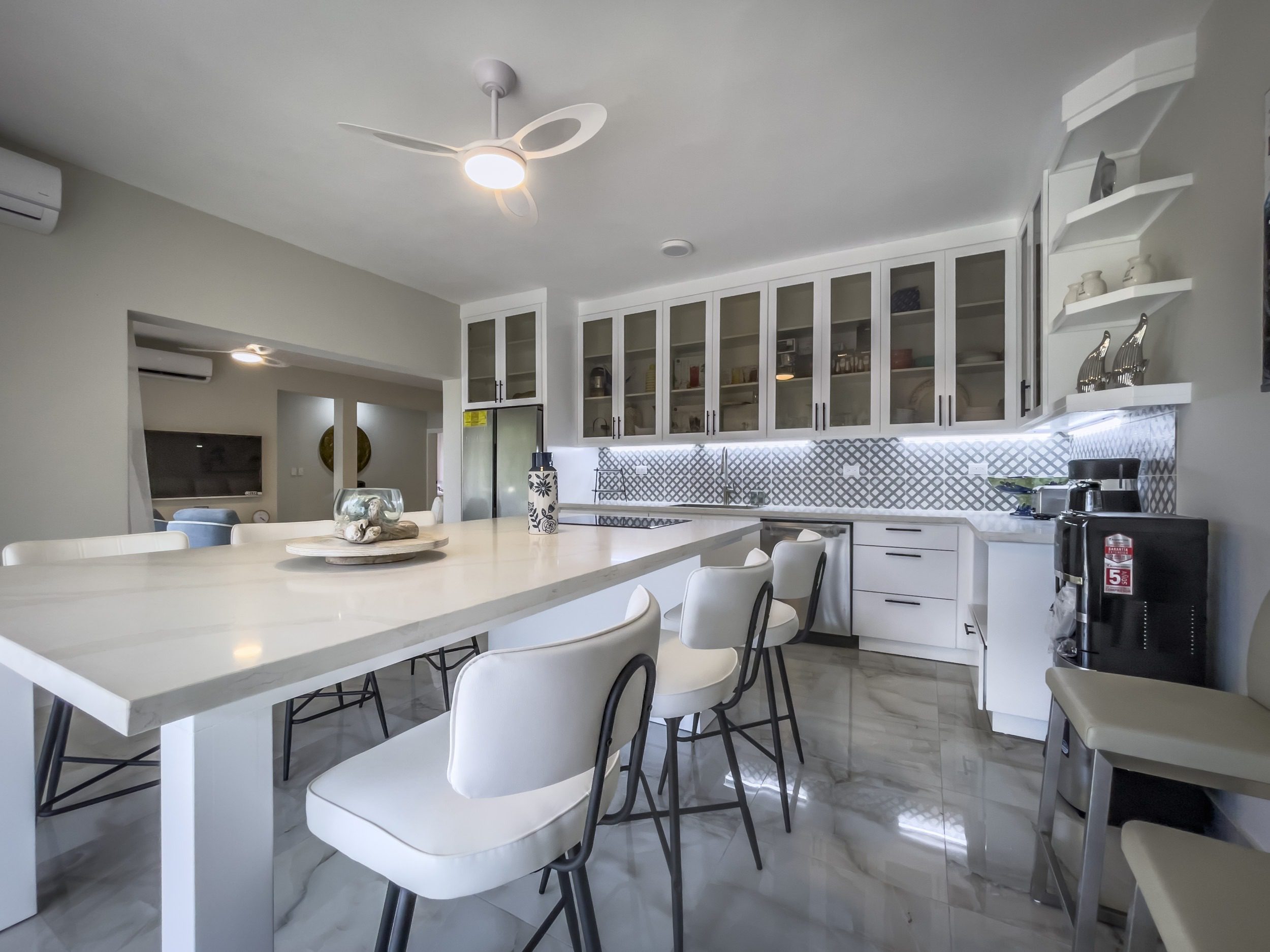 buyDRproperty Modern kitchen with white cabinets, island seating, and a ceiling fan. Sosua Real Estate