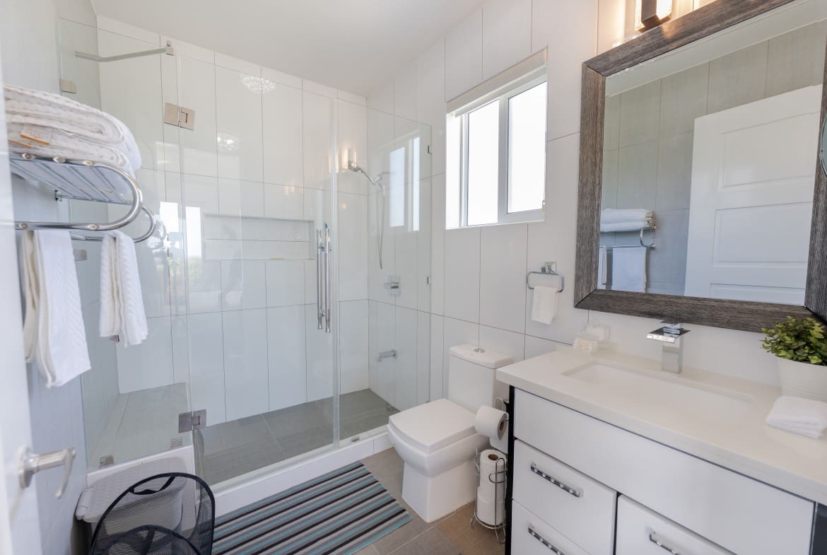 buyDRproperty Modern bathroom in a 5 BR Luxury Villa with glass shower and white tile. Sosua Real Estate