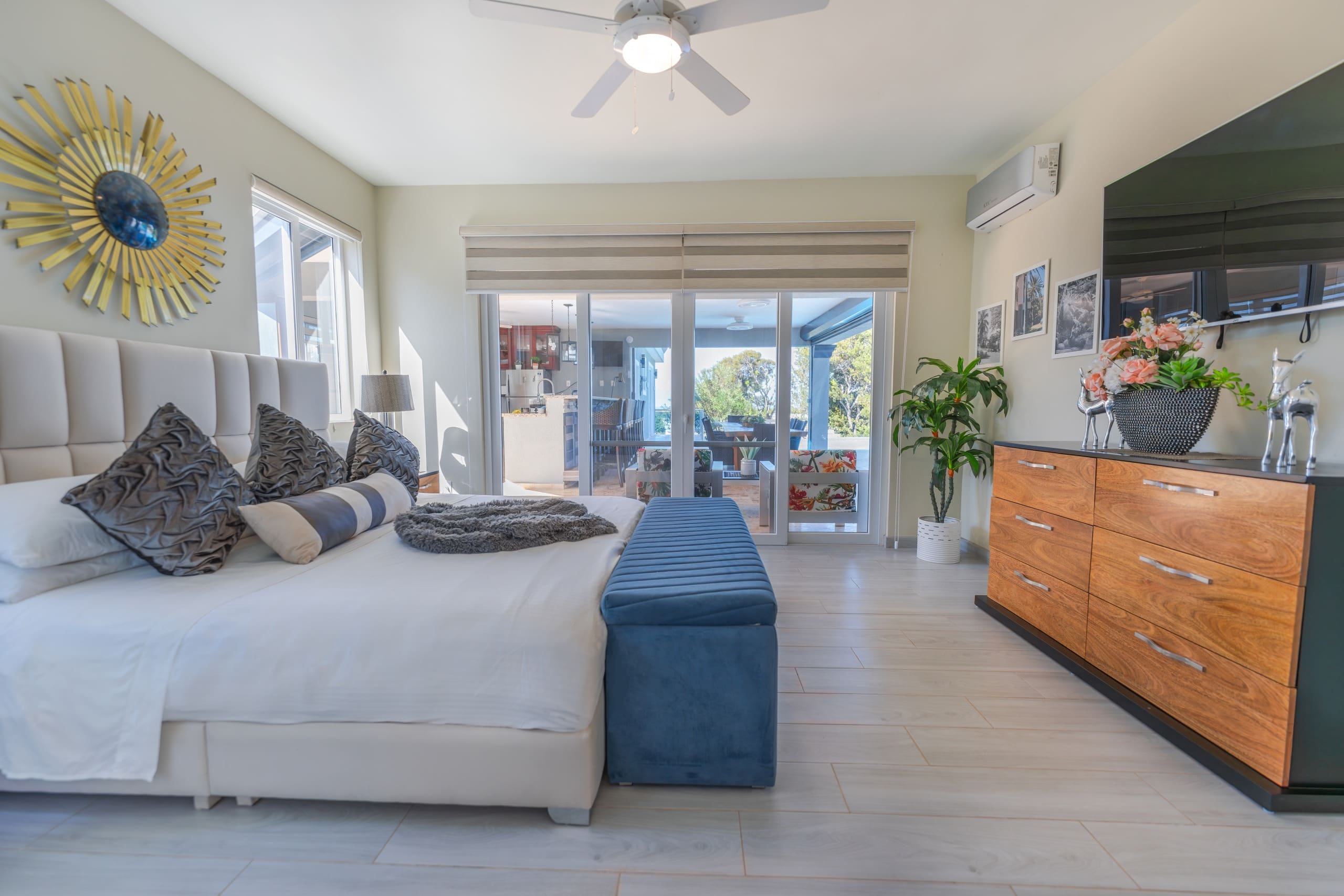 buyDRproperty Luxurious bedroom in a 5 BR Luxury Villa with a king-size bed, a blue bench, and a large TV. Sosua Real Estate