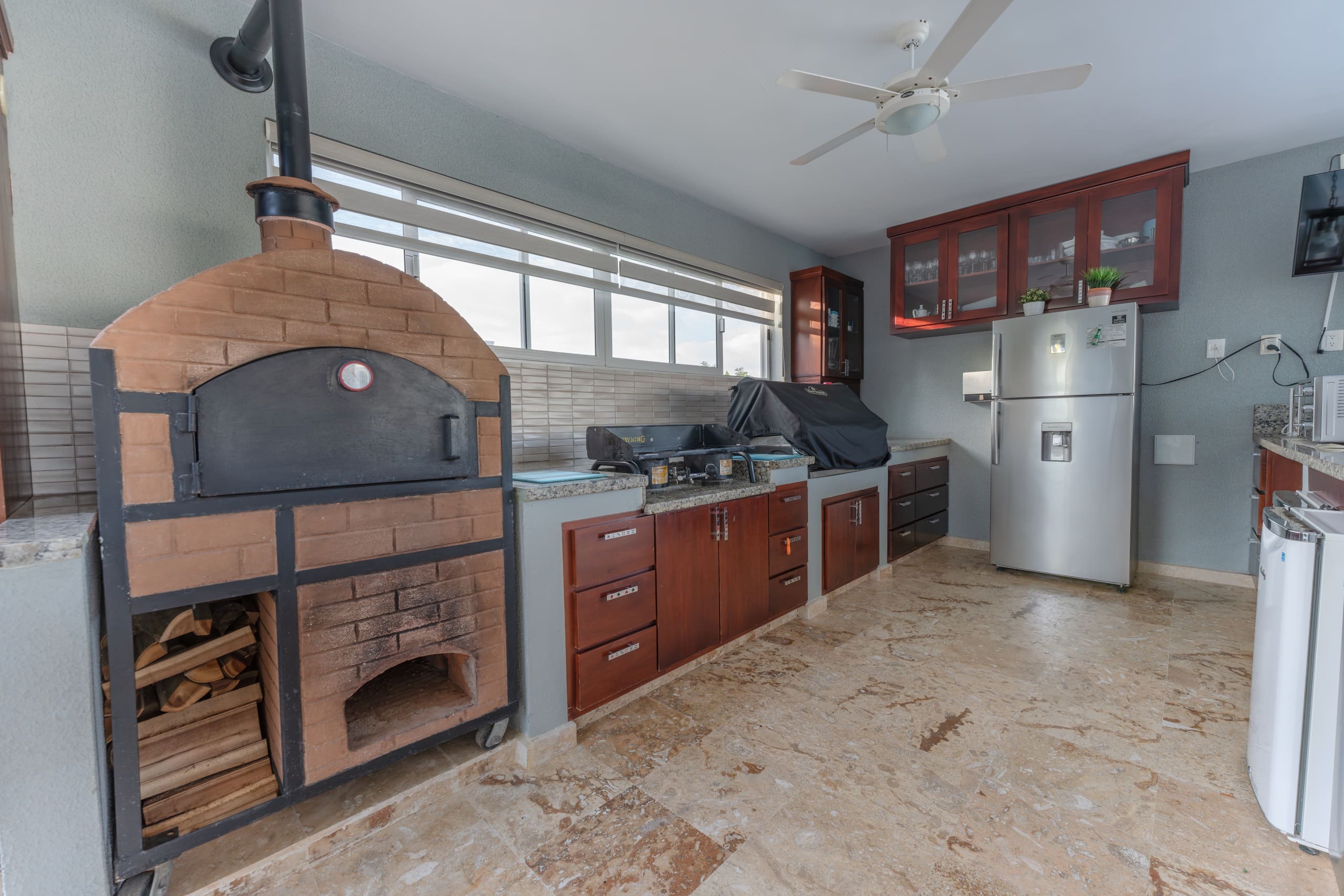 buyDRproperty Outdoor kitchen with brick oven, grill, and refrigerator in a 5 BR Luxury Villa. Sosua Real Estate