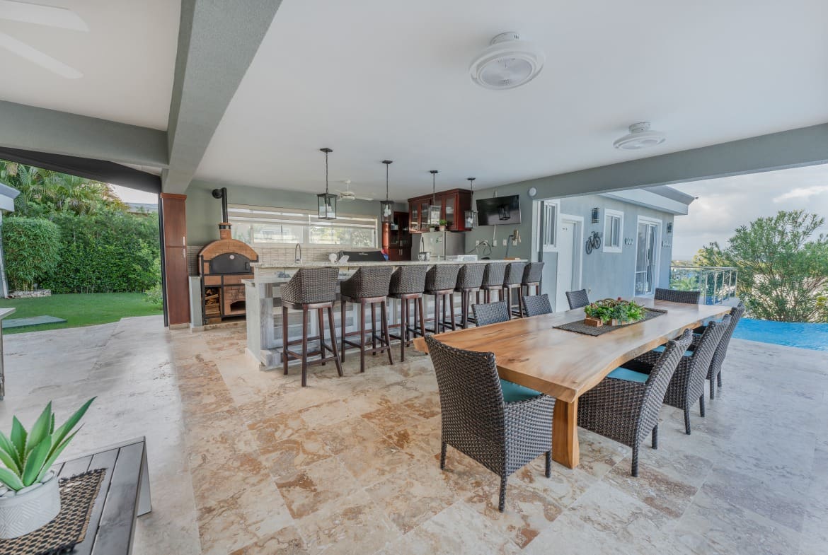 buyDRproperty Outdoor kitchen and dining area at a 5 BR Luxury Villa, featuring a pizza oven and bar seating. Sosua Real Estate