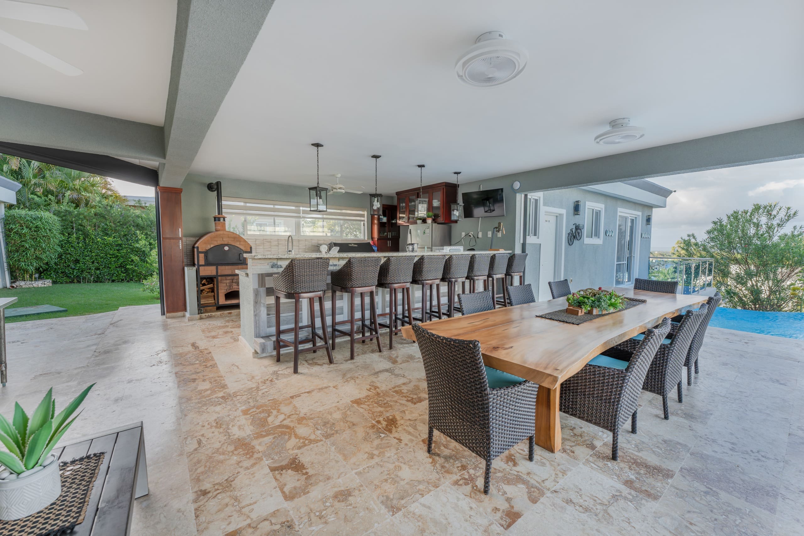 buyDRproperty Outdoor kitchen and dining area at a 5 BR Luxury Villa, featuring a pizza oven and bar seating. Sosua Real Estate