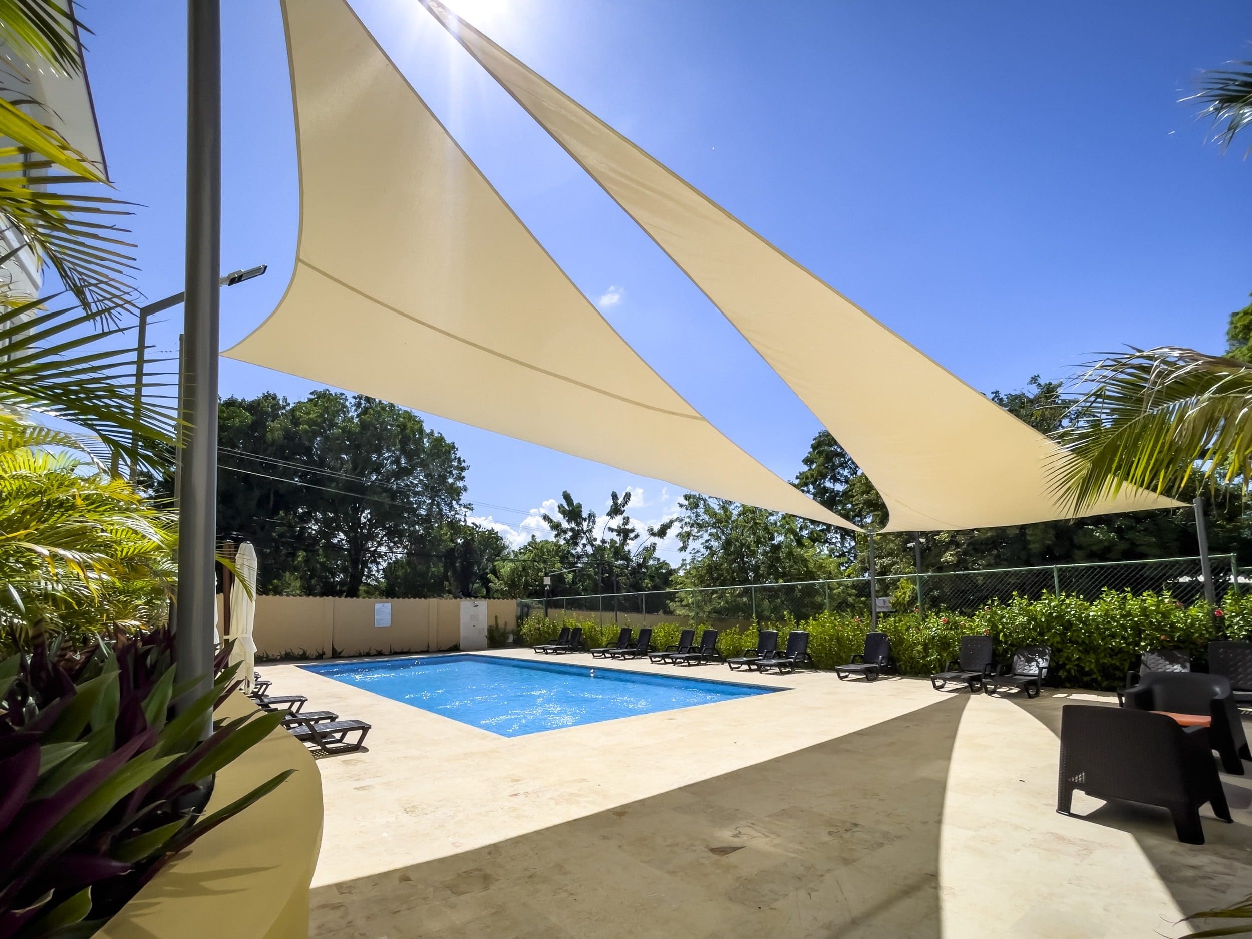 buyDRproperty Pool area with shade sails and lounge chairs at a modern 1-bedroom condo. Sosua Real Estate