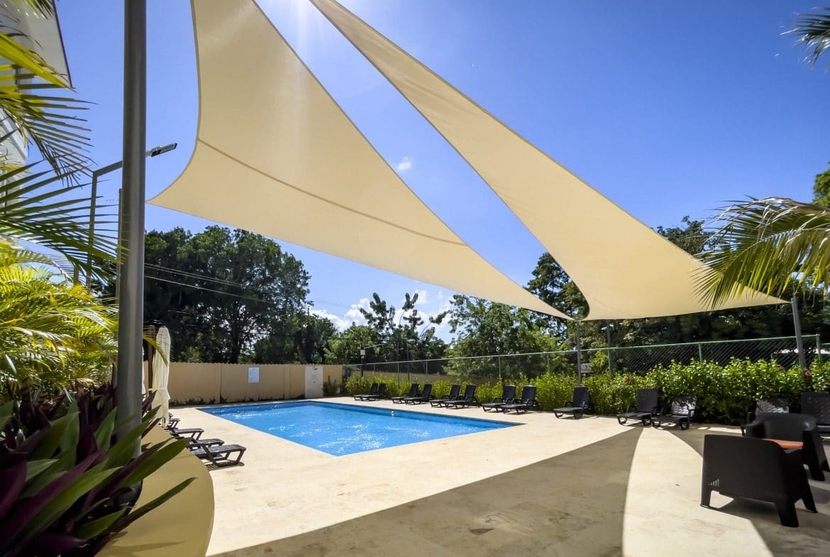 buyDRproperty Swimming pool with shade sails and lounge chairs on a sunny day. Sosua Real Estate