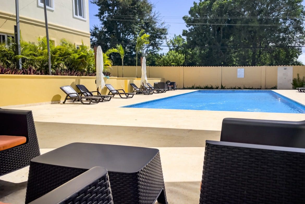 buyDRproperty Poolside lounge area with modern furniture at a modern 1-bedroom condo. Sosua Real Estate