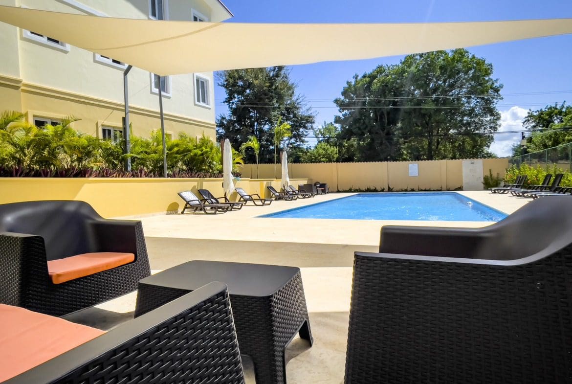 buyDRproperty Poolside relaxation with black wicker furniture at a modern resort Sosua Real Estate