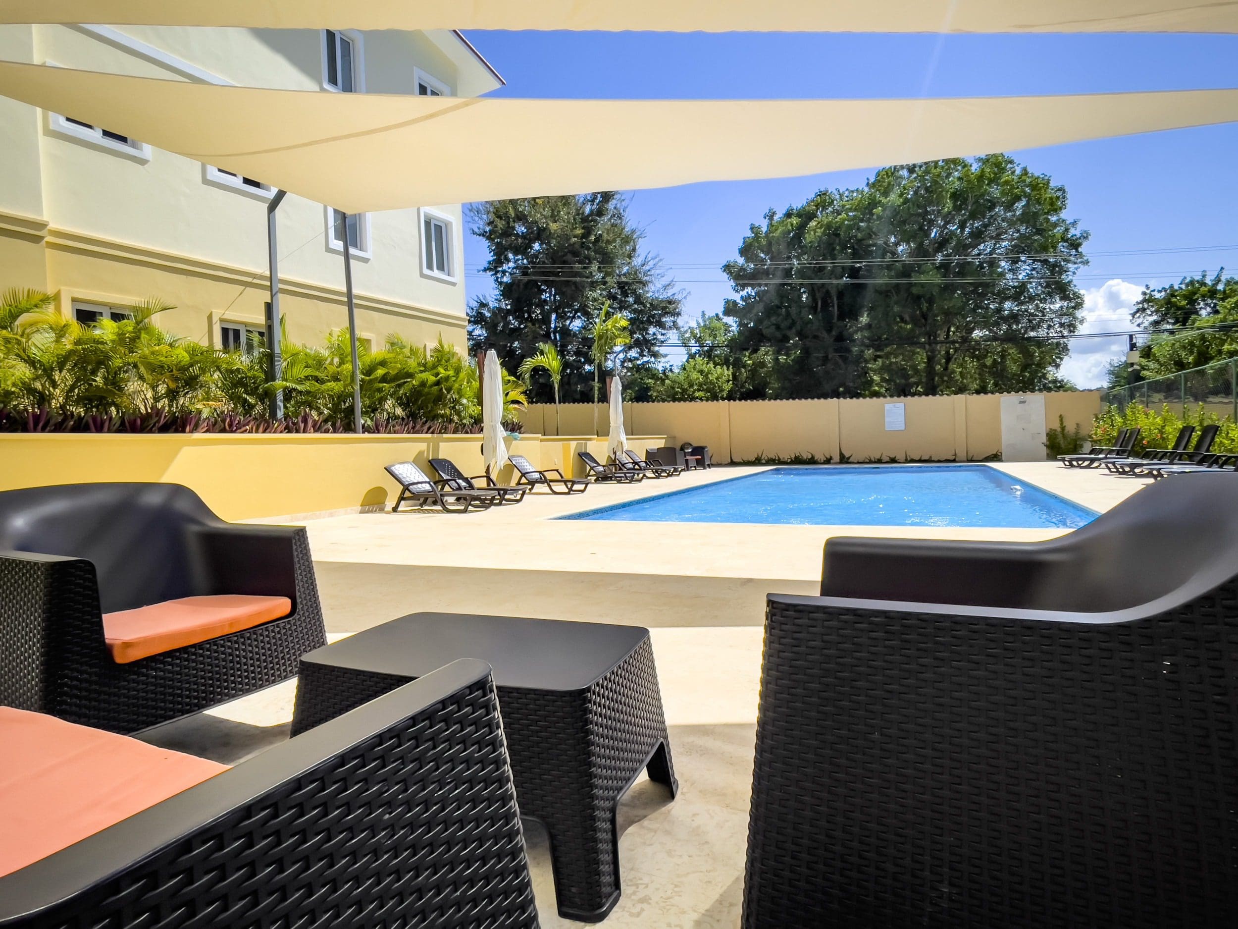 buyDRproperty Poolside relaxation with black wicker furniture at a modern resort Sosua Real Estate