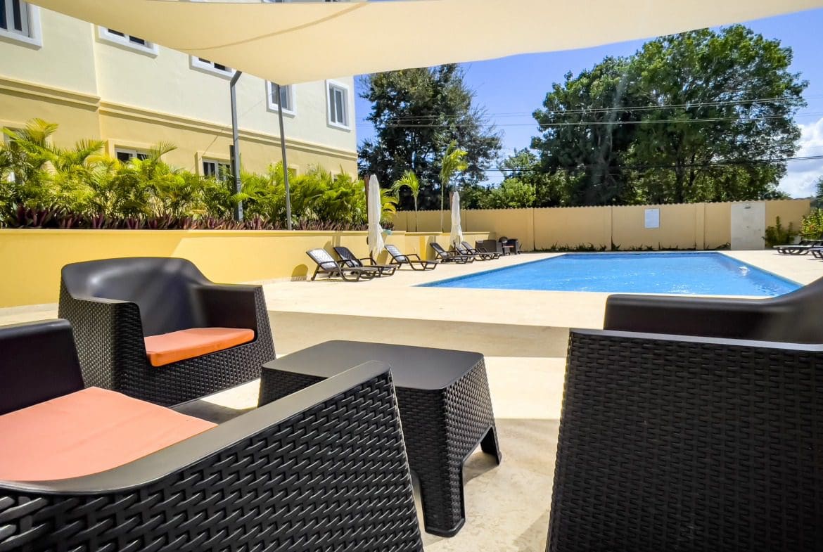 buyDRproperty Poolside lounge area with modern black wicker furniture and pool. Modern Comfort. Sosua Real Estate