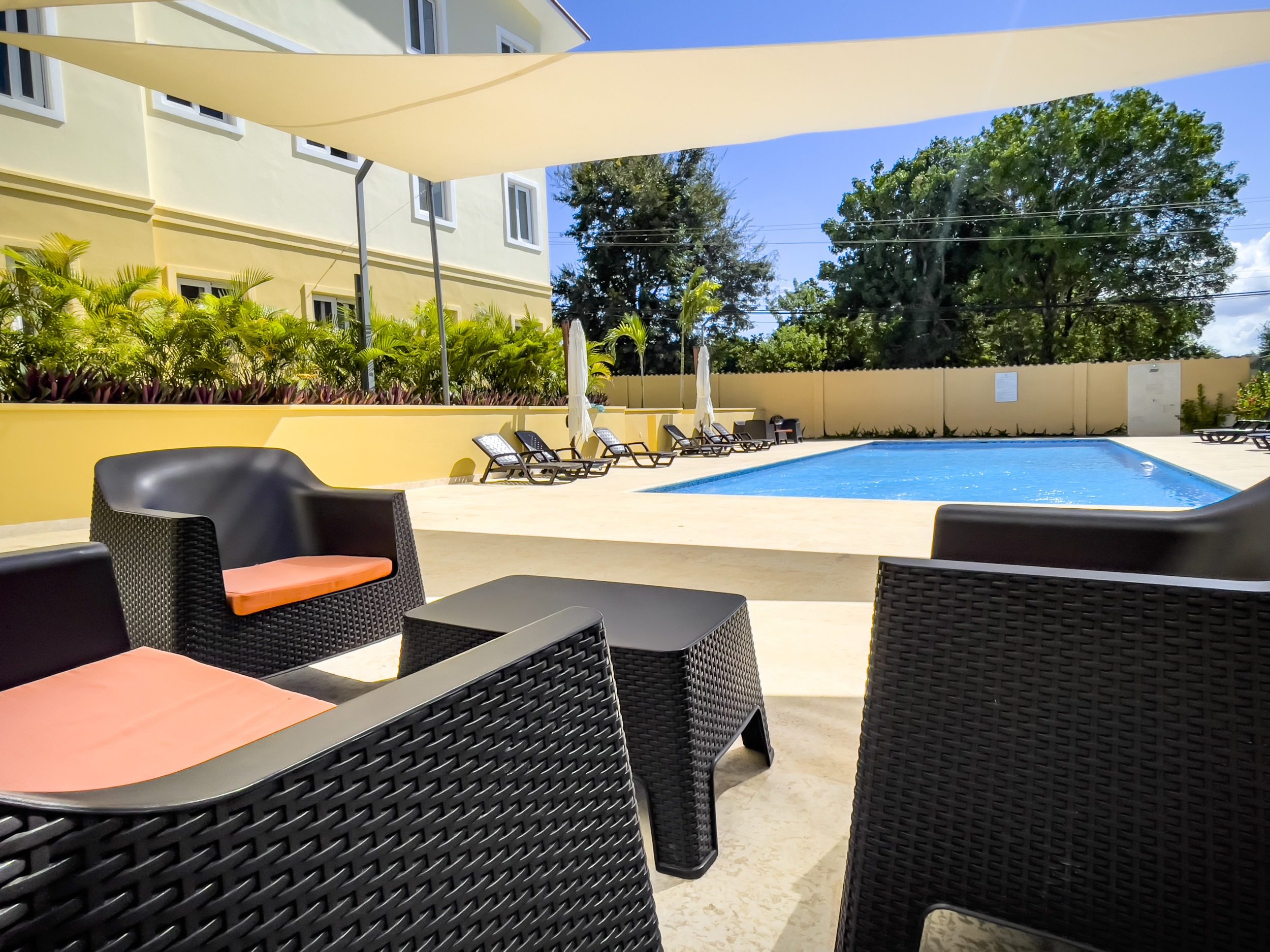 buyDRproperty Poolside lounge area with modern black wicker furniture and pool. Modern Comfort. Sosua Real Estate