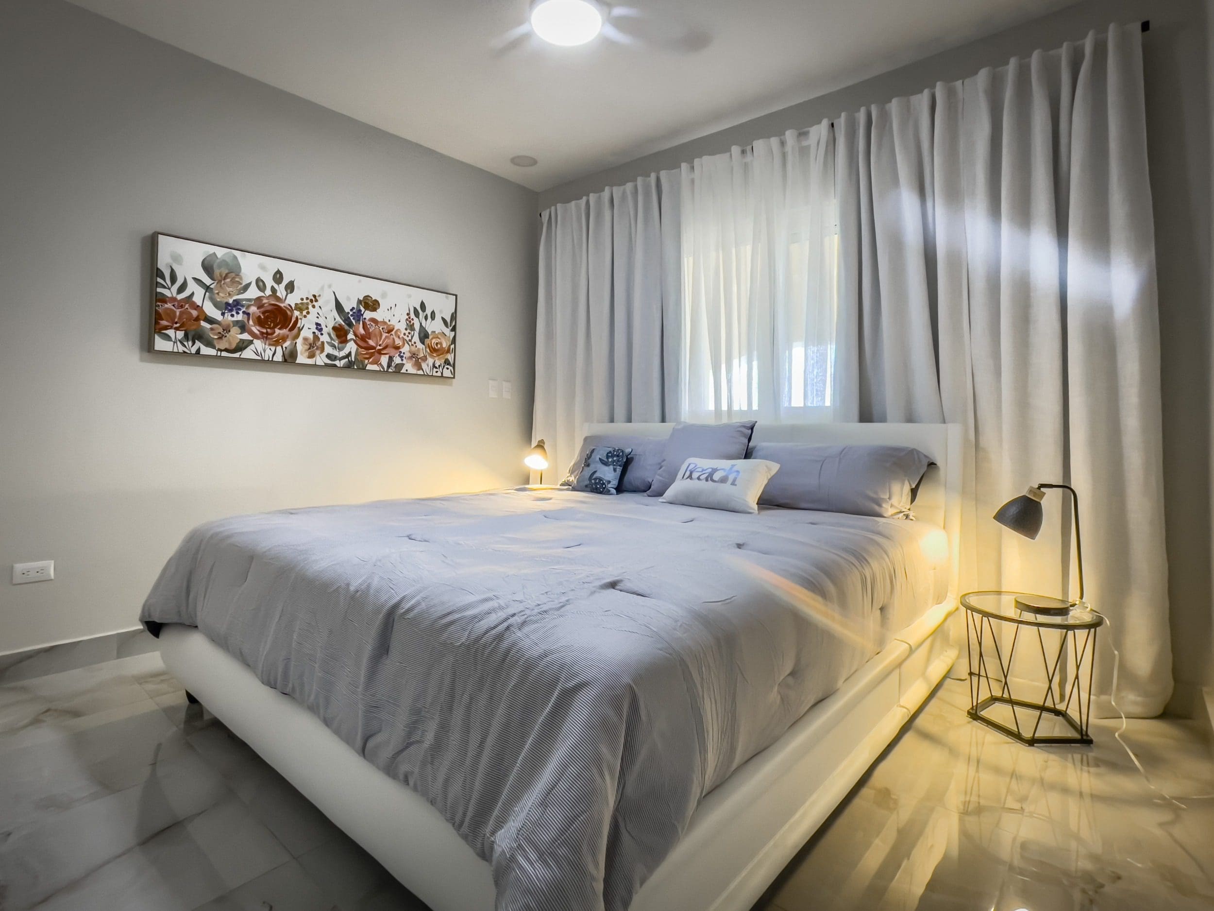 buyDRproperty Cozy 1-bedroom condo bedroom with a comfortable bed and floral artwork. Sosua Real Estate
