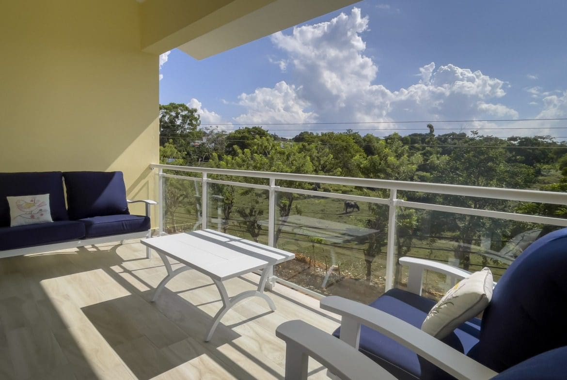 buyDRproperty Balcony of a 1-Bedroom Condo with outdoor furniture overlooking a scenic view. Sosua Real Estate