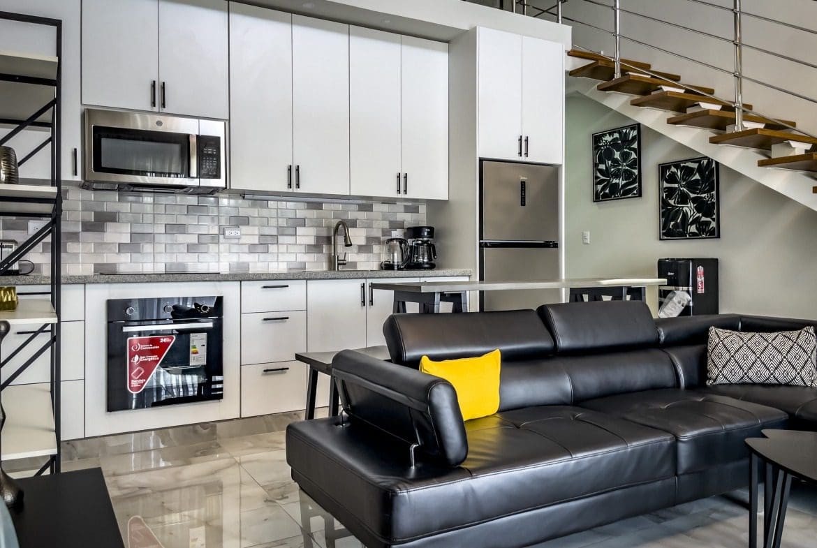 buyDRproperty Modern 1-bedroom condo interior with a kitchen, living area, and loft stairs. Sosua Real Estate