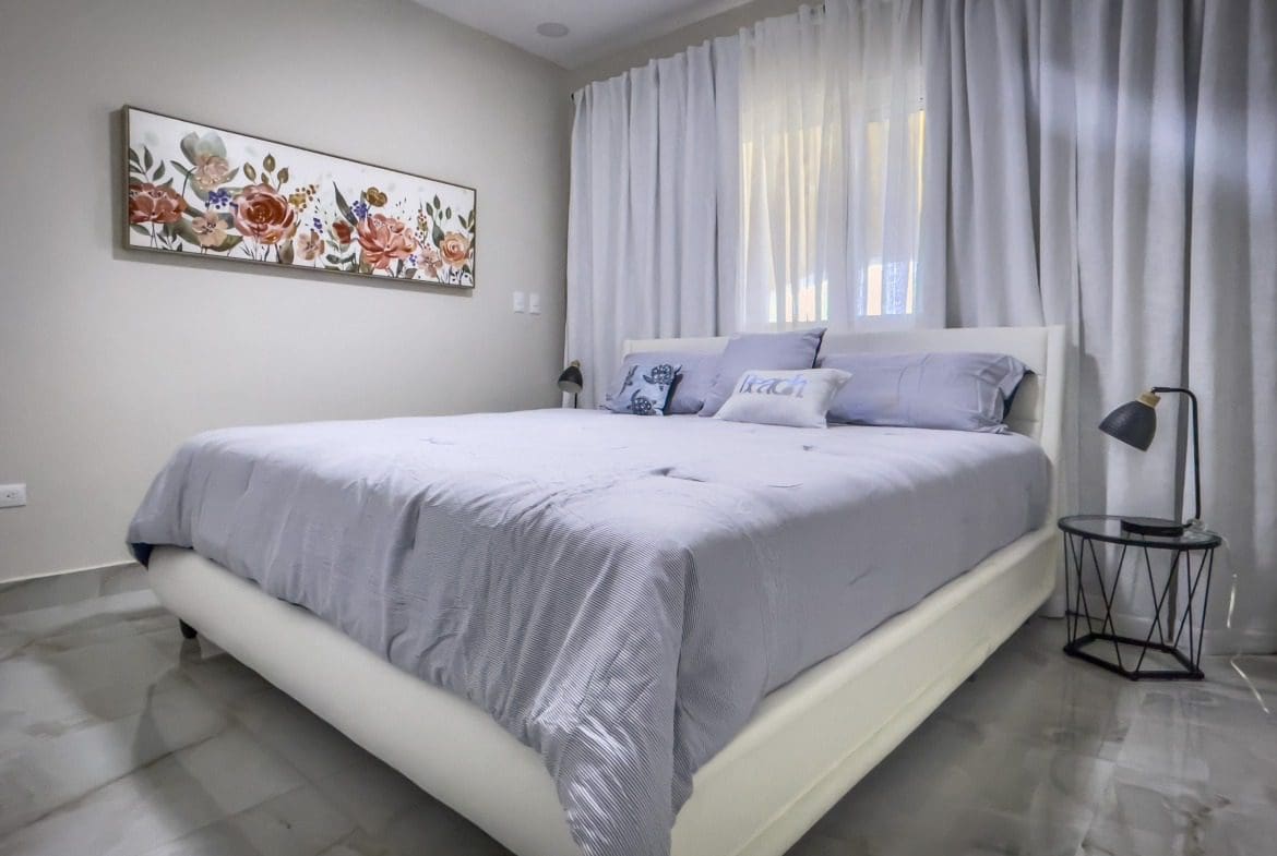 buyDRproperty Stylish 1-bedroom condo bedroom with floral artwork and a modern bed frame. Sosua Real Estate
