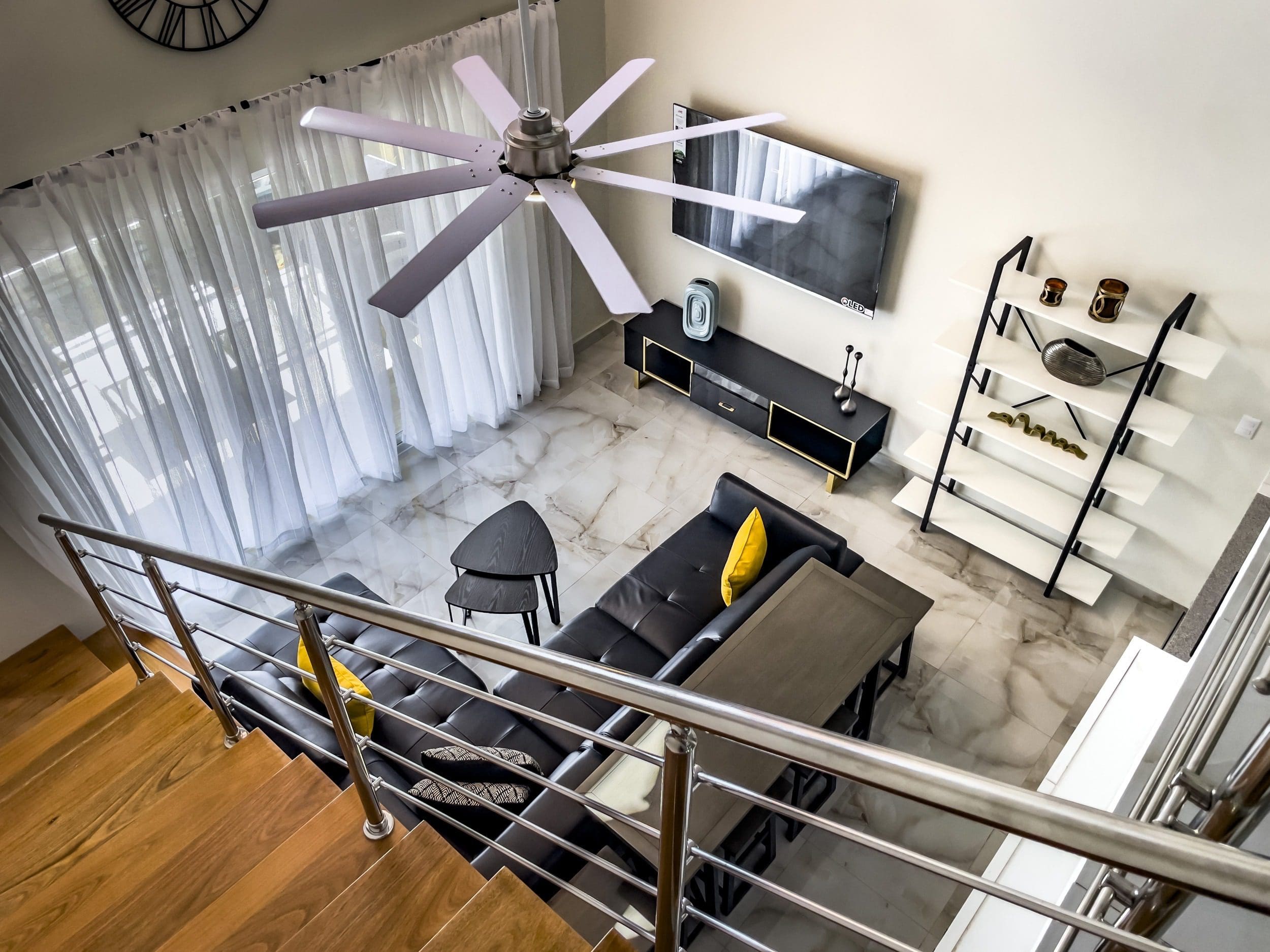 buyDRproperty Modern 1-Bedroom Condo living room with black leather sofa, ceiling fan, and marble floors. Sosua Real Estate