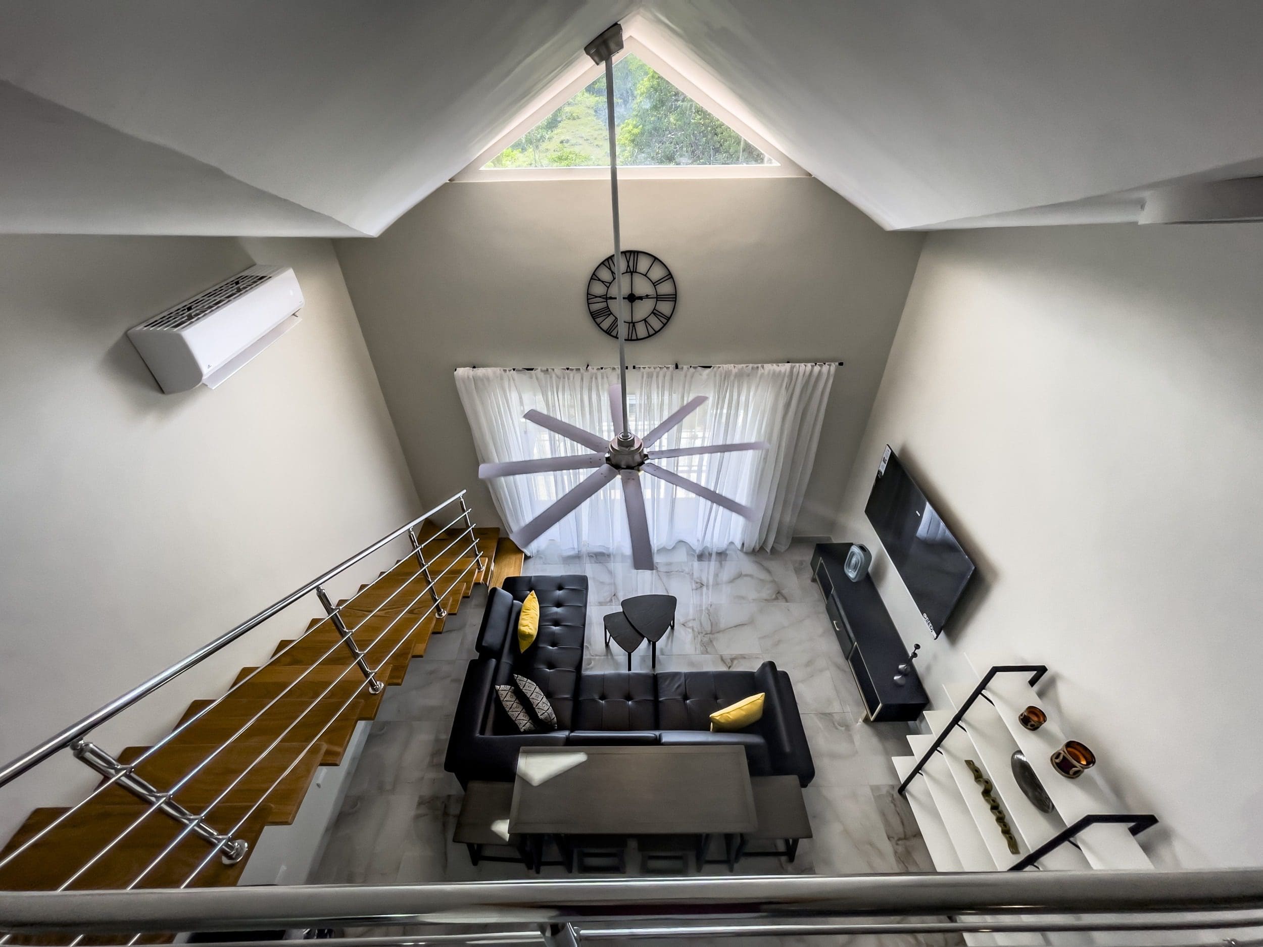 buyDRproperty Modern 1-Bedroom Condo interior with high ceiling, black sofa, and ceiling fan. Sosua Real Estate