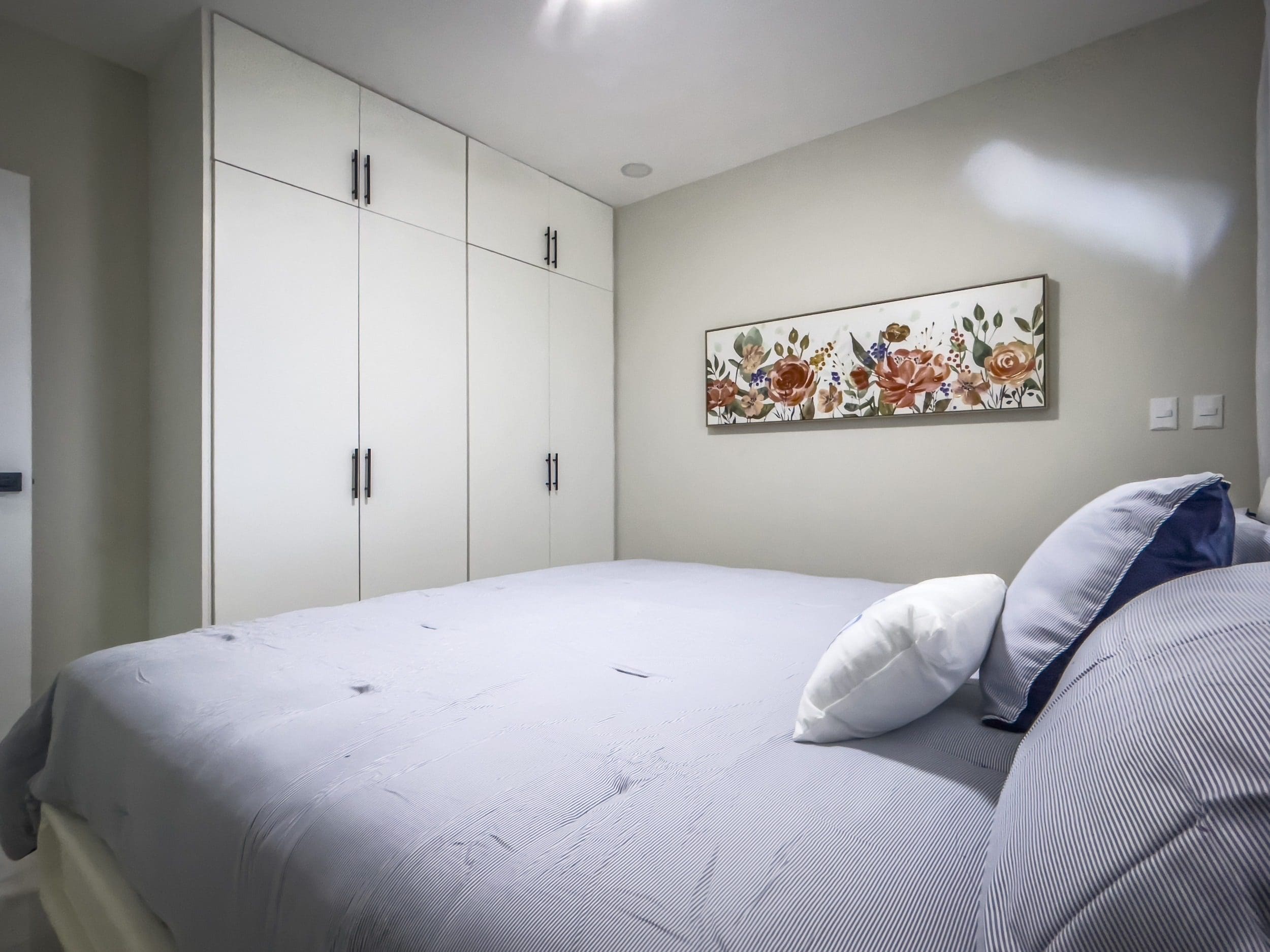 buyDRproperty Bedroom in a 1-bedroom condo with white cabinets and floral artwork. Sosua Real Estate