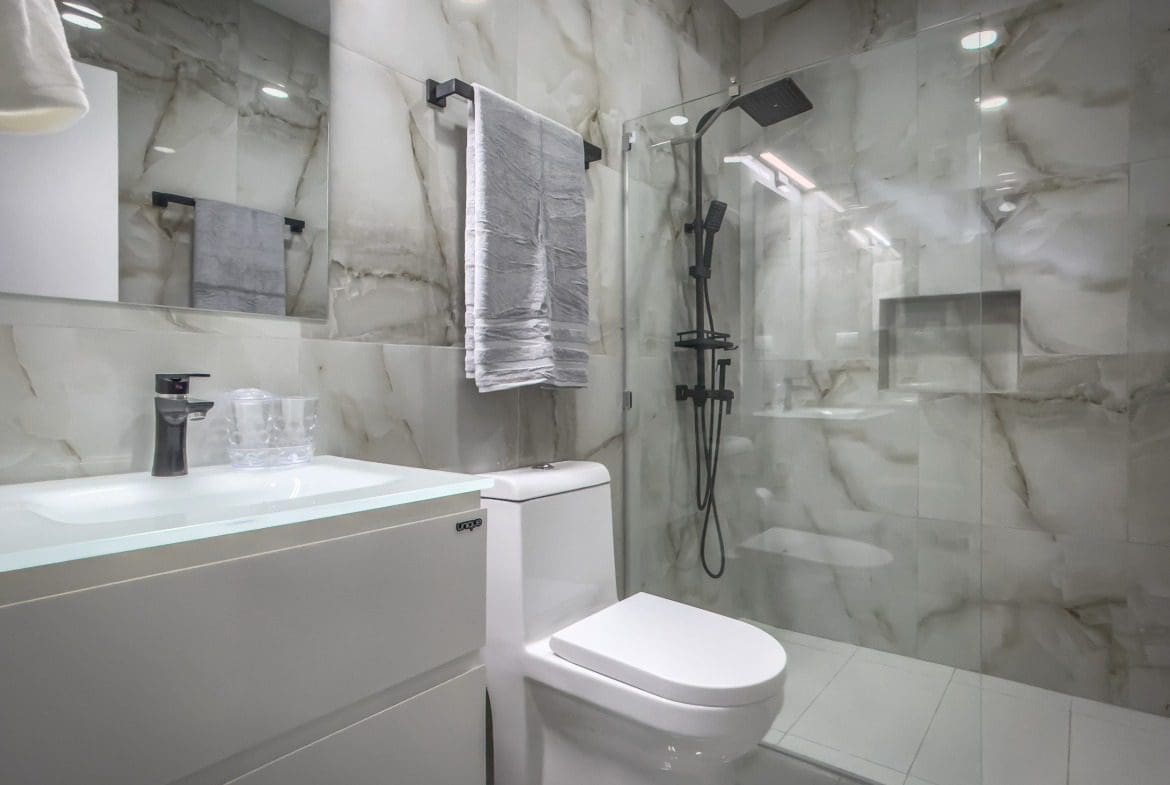 buyDRproperty Modern bathroom in a 1-bedroom condo with marble tile and glass shower Sosua Real Estate