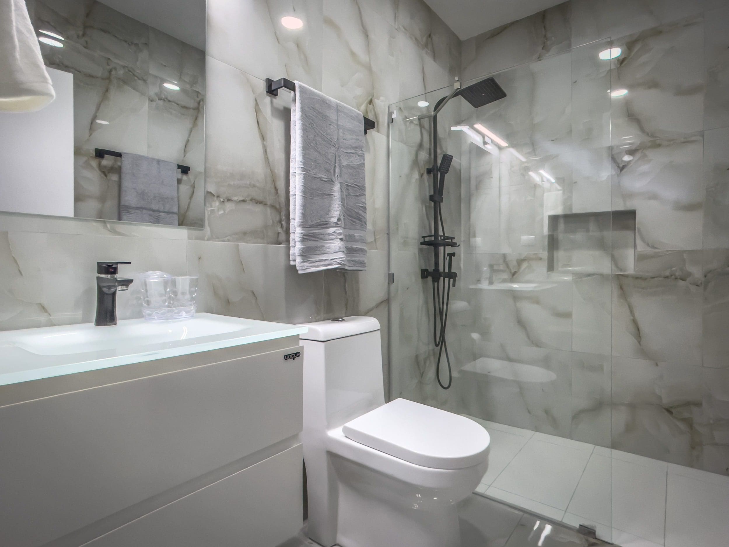 buyDRproperty Modern bathroom in a 1-bedroom condo with marble tile and glass shower Sosua Real Estate