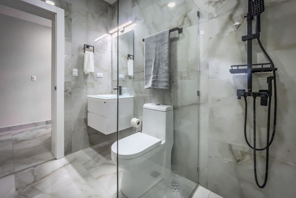 buyDRproperty Modern bathroom in a 1-bedroom condo with marble tile and black shower fixtures. Sosua Real Estate