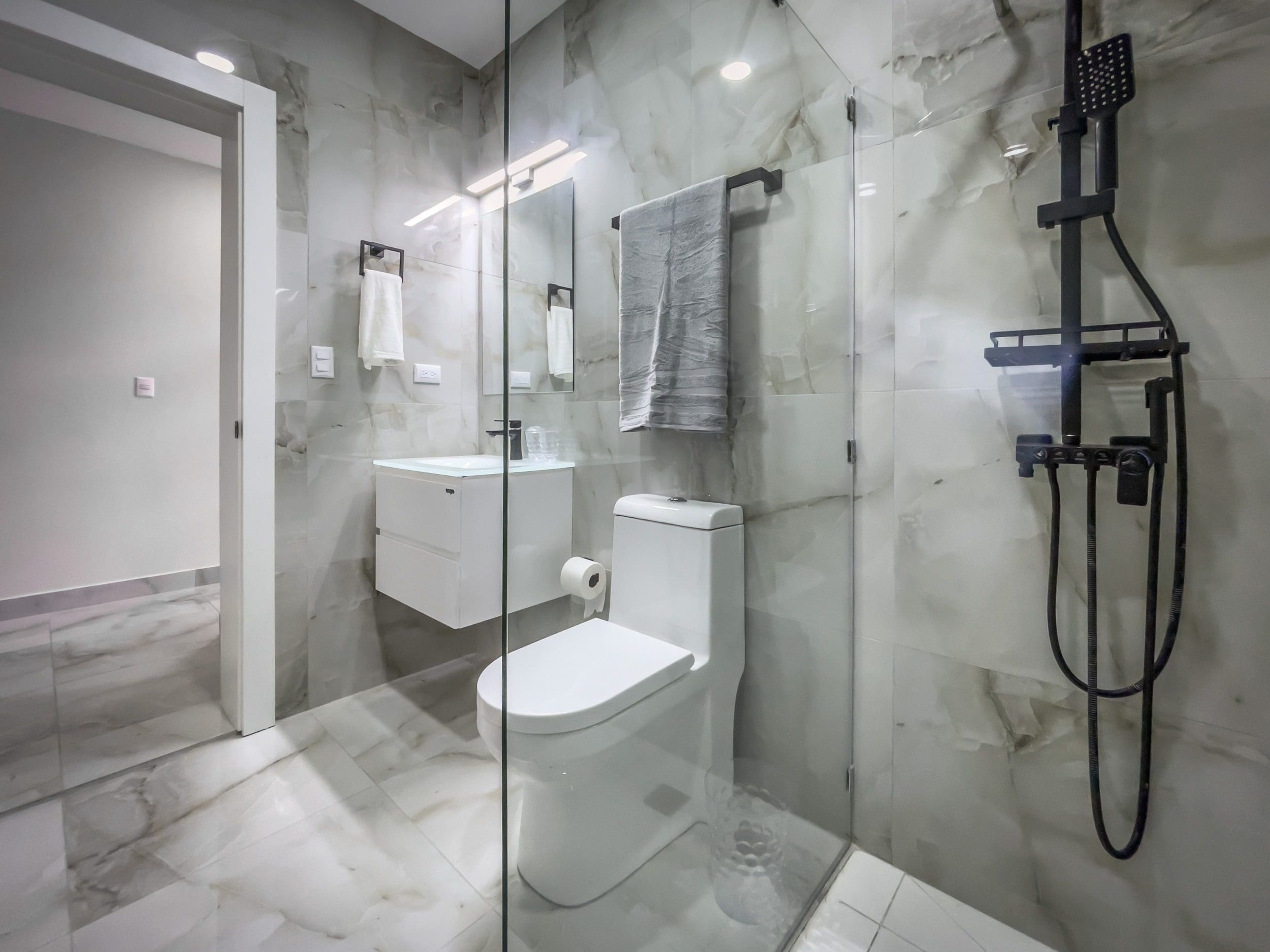 buyDRproperty Modern bathroom in a 1-bedroom condo with marble tile and black shower fixtures. Sosua Real Estate