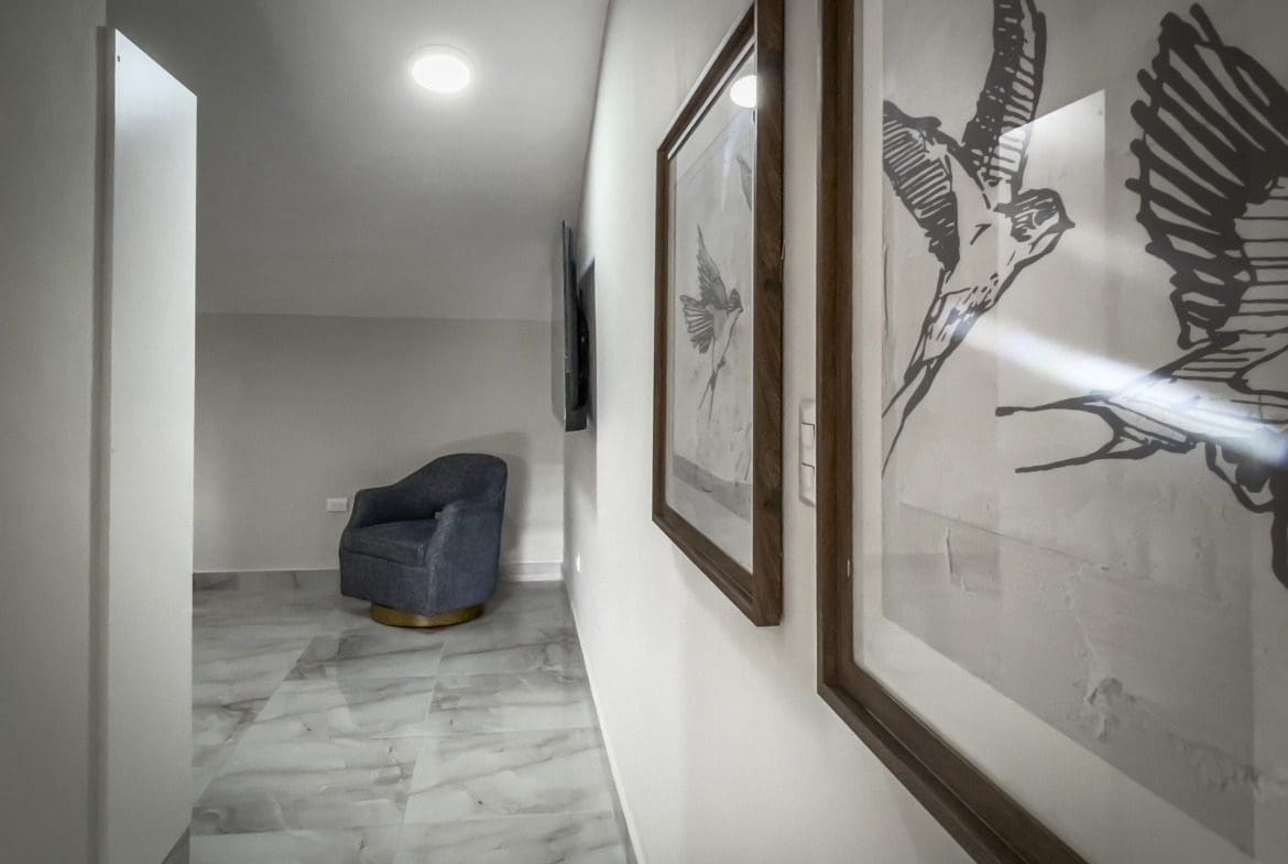 buyDRproperty Stylish 1-bedroom condo hallway with artwork and blue armchair Sosua Real Estate